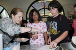 Capt. Jennifer McGee, 12th Contracting Squadron, helps Madison Angelito and Alex Barner make coconut pyramids, a traditional Jewish dessert, on April 22 as part of the Holocaust Days of Remembrance observed here from April 19-26. (U.S. Air Force photo by Don Lindsey)