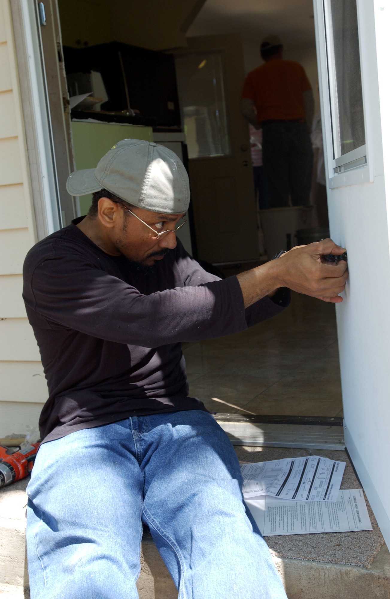 John Hughes, Rebuilding Together volunteer, attaches a closing spring to a new door Saturday. Rebuilding Together assists low-income homeowners with repairs they would not otherwise be able to accomplish on their own. More than 85 members, including family and friends, of Headquarters, Air Force Reserve Command, Robins Air Force Bse, Ga., turned out for the event.