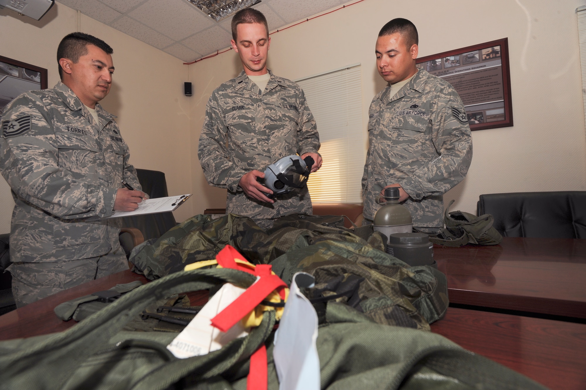 1st Lt. Brad Clark, USAFCENT depot liaison engineer with the 379th Expeditionary Maintenance Operations Squadron, in processes his mobility bag as Staff Sgt. Brandon Sroufe and Tech. Sgt Ricardo Torres, both unit deployment managers for the 379th Expeditionary Maintenance Operations Squadron, inspect and ensure that Lt. Clark has all the proper equipment, April 22, 2009, in an undisclosed location in Southwest Asia.  As UDM's they ensure the unit is not only fully equipped for a hazardous attack, but they also ensure the unit can perform if an attack were to happen.  Lt. Clark is native to Clearfield, Utah and deployed from Hill Air Force Base, Utah and Sergeant Sroufe is native to Ft. Wayne, Ind. and is deployed from Royal Air Force Mildenhall, United Kingdom. and Sergeant Torres hails from Del Rio, Texas and is deployed from Dyess Air Force Base, Texas, in support of Operations Iraqi and Enduring Freedom and Combined Joint Task Force - Horn of Africa.  (U.S. Air Force Photo by Staff Sgt. Joshua Garcia/released)