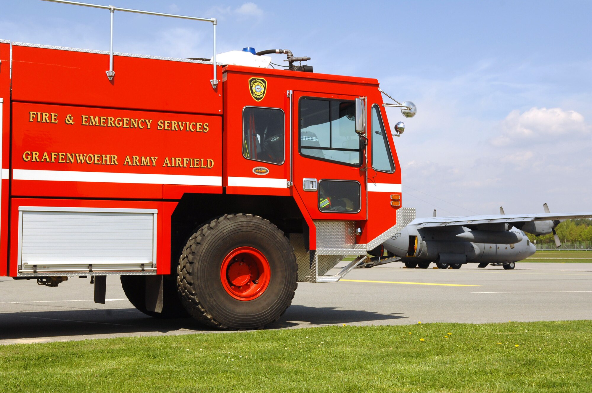 A fire truck from Grafenwoehr Army Airfield, Germany, stands-by as a C-130E from the 86th Airlift Wing prepares to fly members from the 173rd Airborne Brigade Combat Team to complete their quarterly training jump, April 22, 2009. The 173rd ABCT relies solely on the support of the 86th Airlift Wing to maintain their quarterly proficiency jump requirements. (U.S. Air Force photo by Tech. Sgt. Michael Voss)