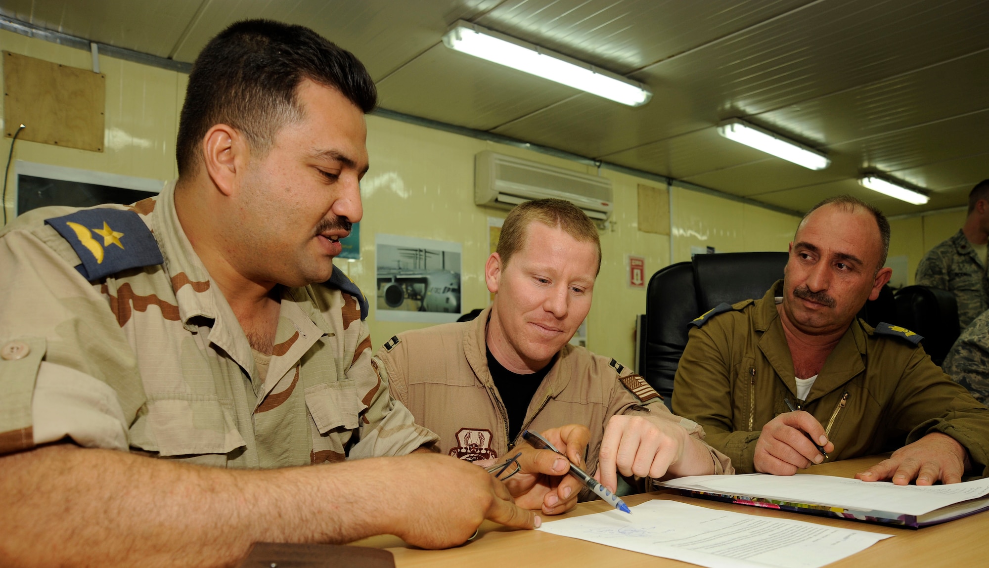 Capt. Justin Allen, Coalition Air Force Training Team, plans out air operations with Iraqi air force Second Lieutenant Firas and Major Muaamur Fuad at Camp Victory, Iraq April 21, 2009. Major Fuad and Lieutenant Firas are part of ten Iraqi air force officers receiving the first course of U.S. Joint Air Operations Planning. The course is based on a two week curriculum taught at Maxwell-Gunter Air Force Base, Ala. The seven day course is intended to give the Iraqis the needed tools to build an operational level planning capacity for the Iraqi air force.  After course completion, the Iraqi officers are going to write the first Iraqi air operations plan. Captain Allen is one of many Air Force advisors helping with the course.  Captain Allen is deployed from Tyndall AFB, Fla. and a native of Pryor, Okla. (U.S. Air Force photo by Senior Airman Jacqueline Romero)