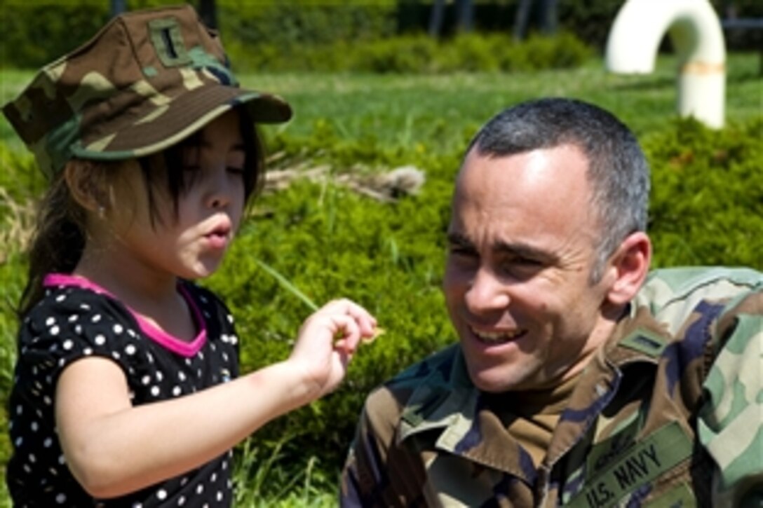 U.S. Navy Lt. j.g. Angel Olivera spends time with his daughter during a ¨Month of the Military Child" event at Naval Air Station Sigonella, Sicily, April 24, 2009. U.S. sailors visited their children's classrooms at Stephen Decatur Elementary School and then surprised them with a picnic lunch in the afternoon.