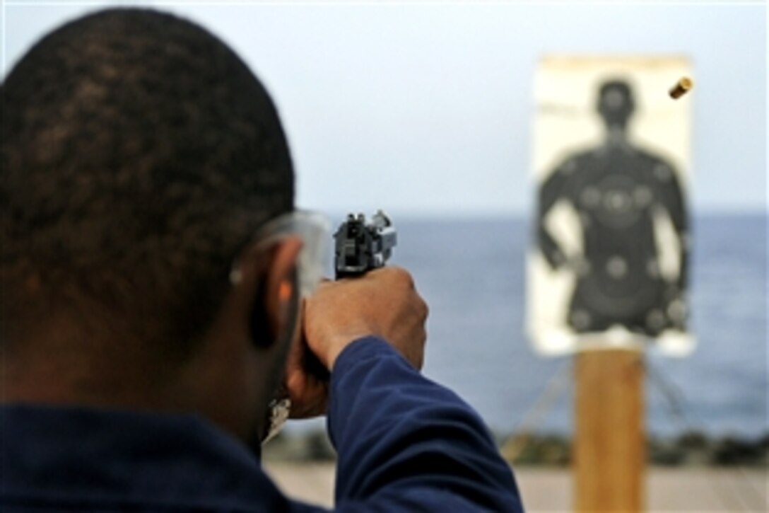 U.S. Navy Petty Officer 3rd Class Chazz Brown fires a 9mm pistol during a small arms qualification aboard the amphibious command ship USS Blue Ridge in the Pacific Ocean, April 24, 2009. Brown is an operations specialist.