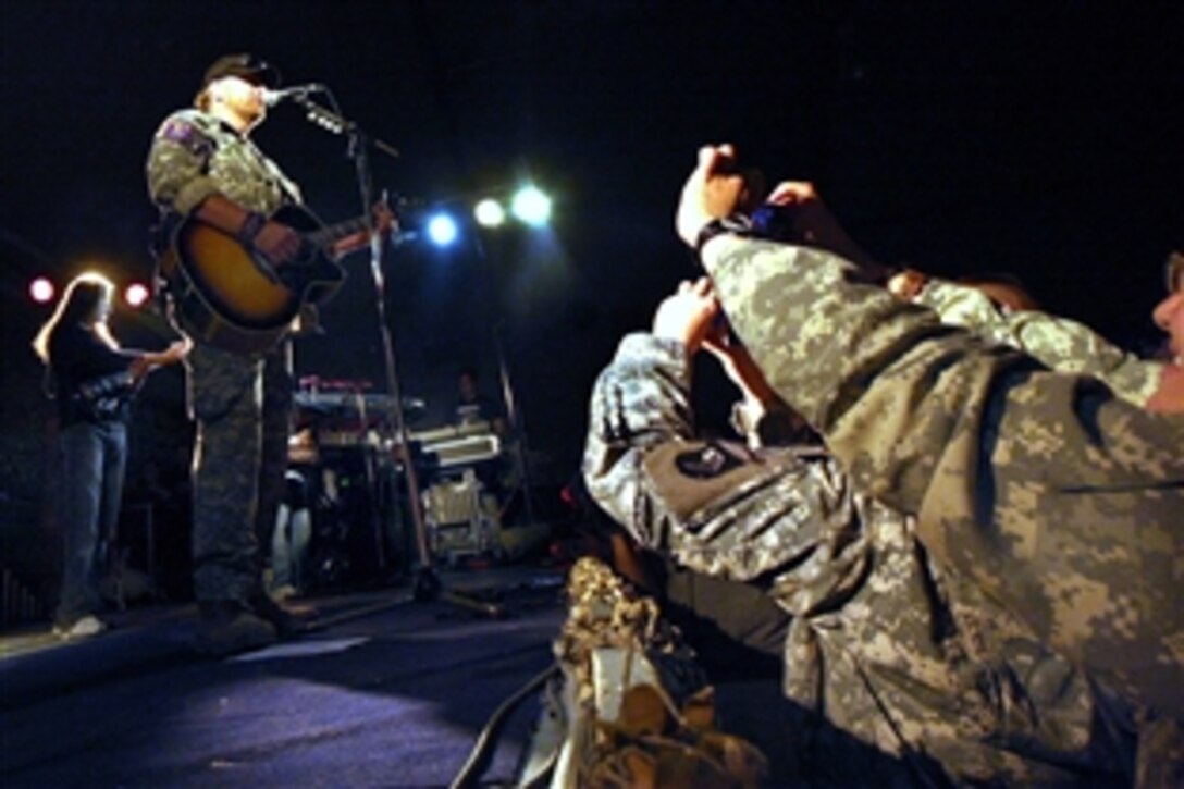 U.S. troops crowd the stage to take a photo of Toby Keith during his concert on Bagram Air Field, Afghanistan, April 27, 2009. This was Keith's seventh USO tour.