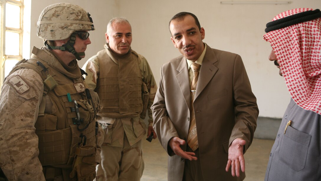 Chief Warrant Officer Matthew Lovely, officer-in-charge of Civil Affairs Team 6 Detachment West, Civil Affairs Group, Regimental Combat Team 8, talks with the sub-Mayor of Tallabtah, Abdulrhman Khaled, and the Khabbaza village official, Jamal Dham Muhammad,  about the results of a school renovation in Khabbaz, Iraq April 29, 2009.  Marines along with the Iraqi people helped to bring much needed renovations to the school.