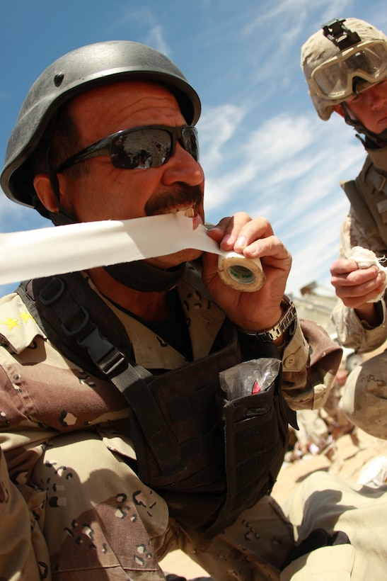 An Iraqi role player with the Advisor Training Group helps Marines and sailors with a military transition team as they attend to fake casualties after an attack from an improvised explosive device May 1 at the Combat Center’s Gypsum Ridge training area.