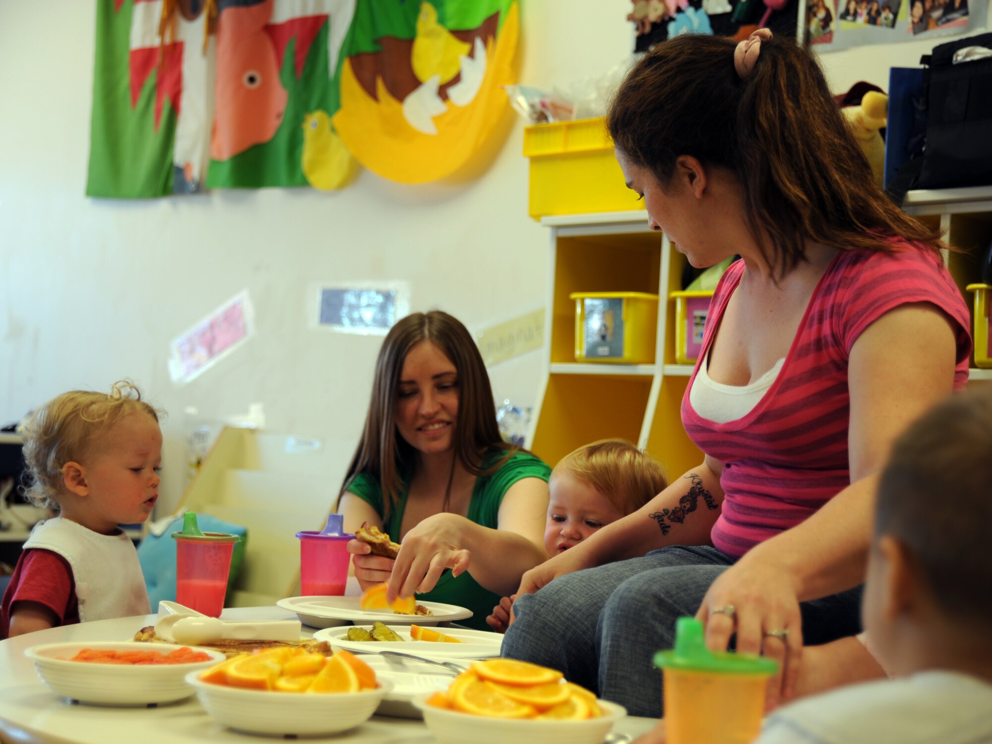 MCCONNELL AIR FORCE BASE, Kan. -- Ethan Crandall, 20 months, son of Staff Sgt. Amanda Currier, 22nd Air Refueling Wing public affairs, watches as childcare provider Nichole Stark and daughter Haylie Stark, 14 months, eat lunch together. Childcare provider KerryAnn Floria passes out oranges, during a parent child luncheon held at the Child Development Center, April 23. The luncheon provided parents and children an opportunity to spend time together and bond during the working day. (Photo by Senior Airman Laura Suttles)
