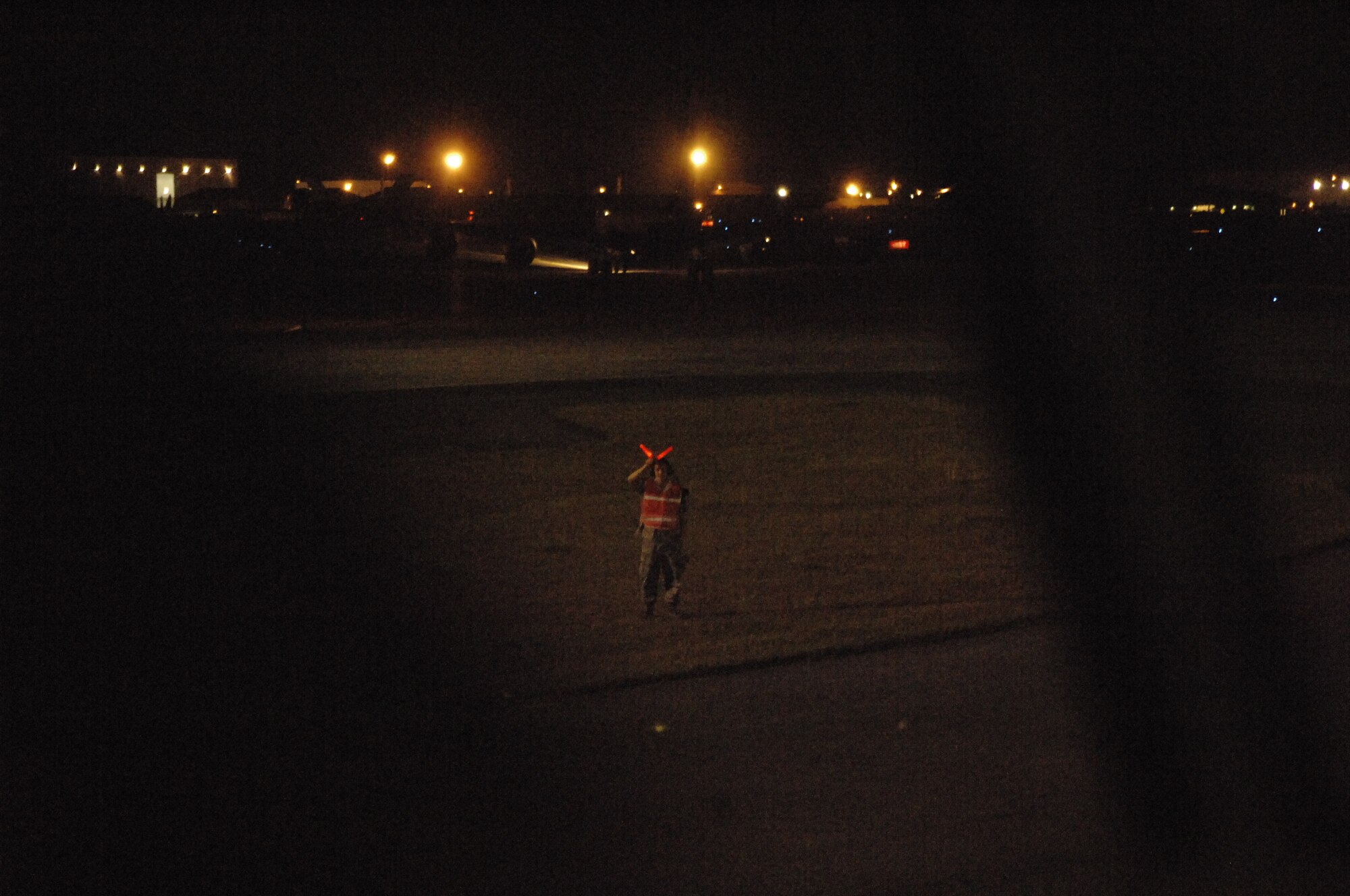 A Team McConnell member using flashlights, instructs a pilot to hold position until clearance is given for takeoff. Airmen use a set of hand gestures to communicate with pilots guiding them to and from the runway. (Photo by Staff Sgt. Ronald Lafosse)