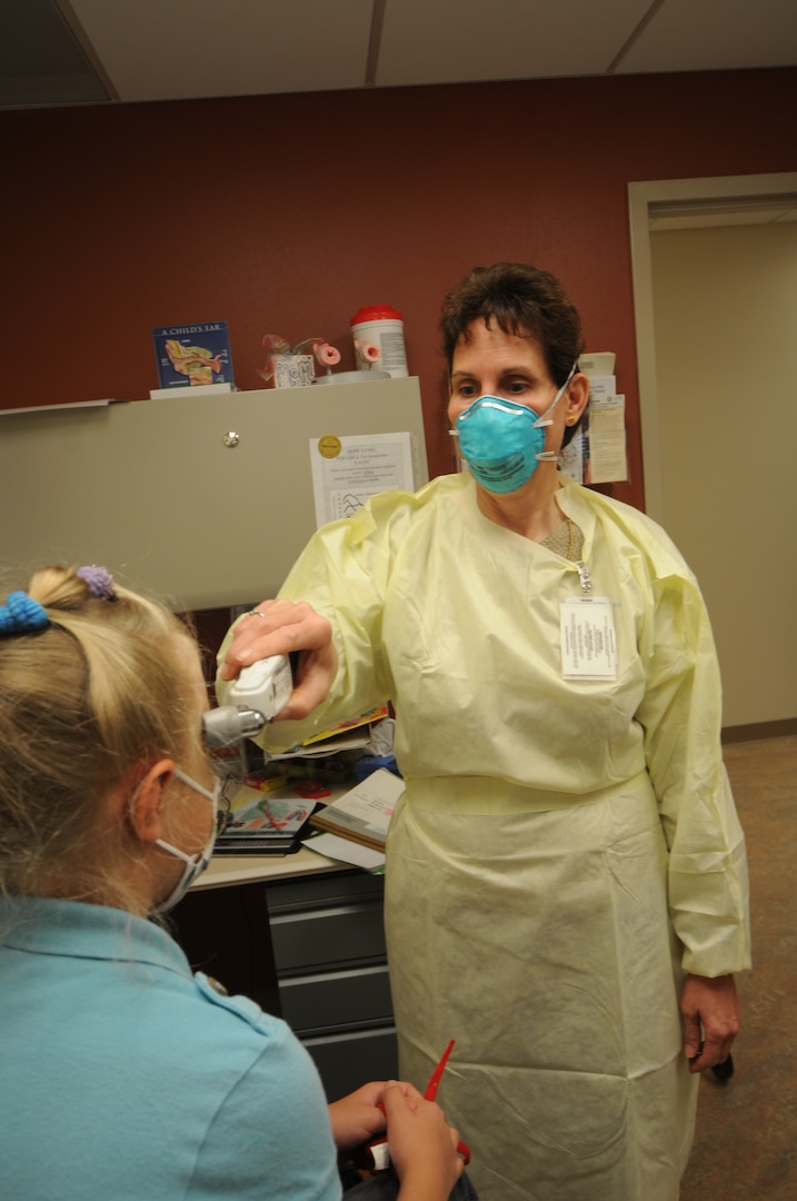 Retired Lt. Col. Kathy Hagerman, a pediatric nurse practitioner, takes the temperature of a patient at the 12th Medical Group April 29. Ms. Hagerman was the first to perform a throat culture on two teenagers suspected of contracting the H1N1 , or swine, influenza recently. U.S. Air Force photo by Steve White)

