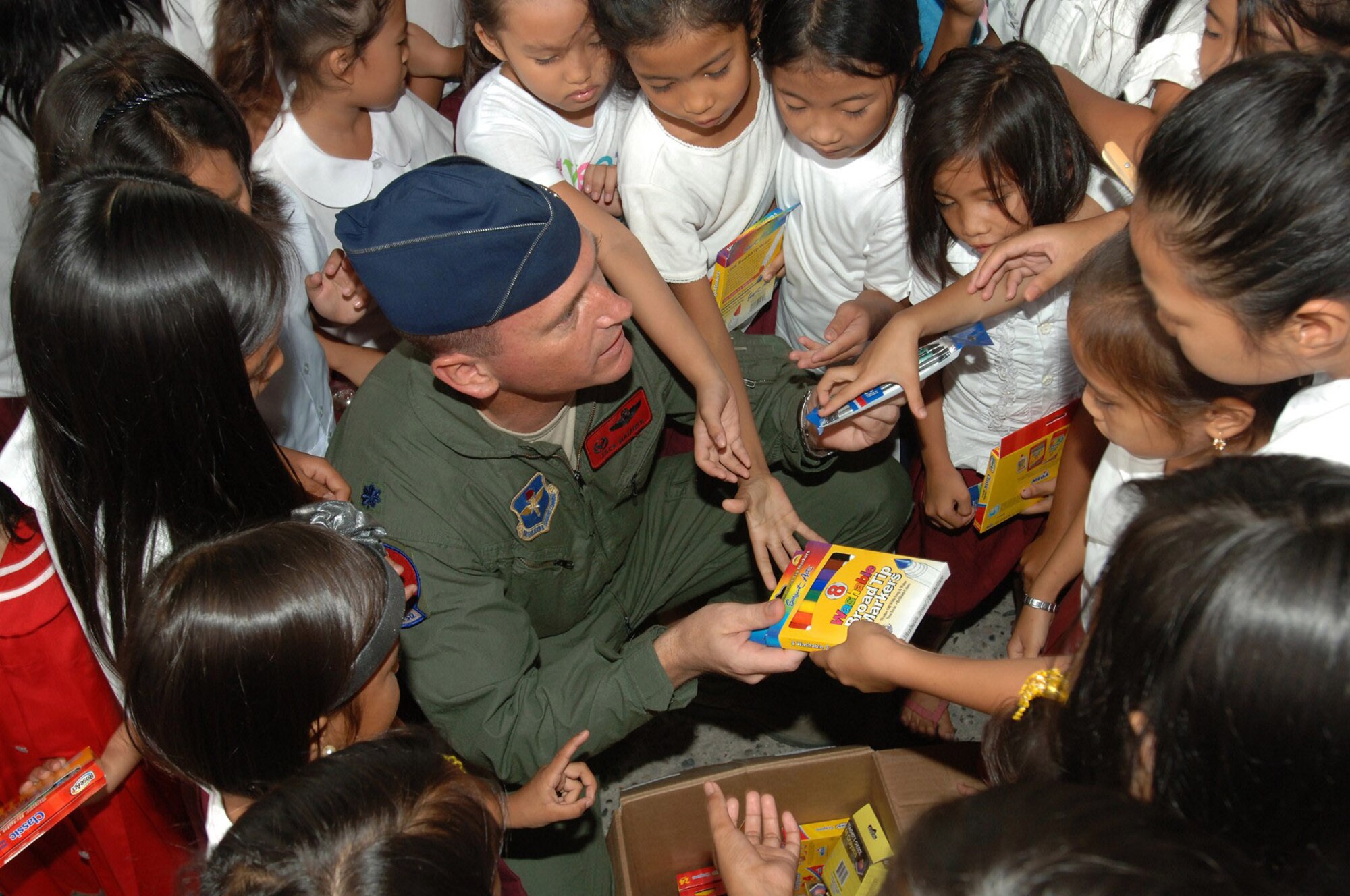 Lt. Col. Jack Maixner hands out school supplies to Filipino children at the Sapangbato village community center as part of a volunteer community relations event held April 24 and 25 at Angeles City, Philippines. Colonel Maxiner is the 63rd Fighter Squadron commander at Luke Air Force Base, Ariz. (U.S. Navy photo/Petty Officer 2nd Class Robert Clowney) 
