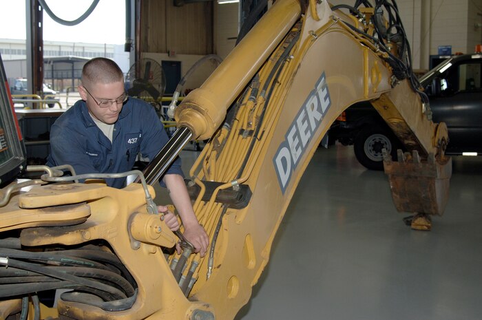 Senior Airman Jacob Thomas tightens hydraulic lines for the operation of the clam shell bucket on a backhoe at the vehicle maintenance shop here April 29.  The backhoe is used for general digging and was brought into vehicle maintenance for an inoperable clam shell bucket. Airman Thomas is assigned to the 437th Logistics Readiness Squadron as a multi-purpose maintenance journeyman. (U.S. Air Force photo/Staff Sgt. Marie Cassetty)(RELEASED)