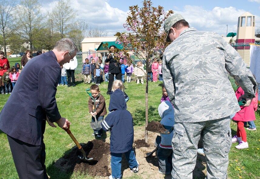 Austin Short, Delaware State forester, Col. Todd Emmert, 436th Mission Support Group commander, and children from the Dover Air Force Base Child Development Center plant a tree in front of the CDC recently. Dover AFB was named a Tree City USA for the 17th year in a row. (U.S. Air Force photo/Tom Randle)