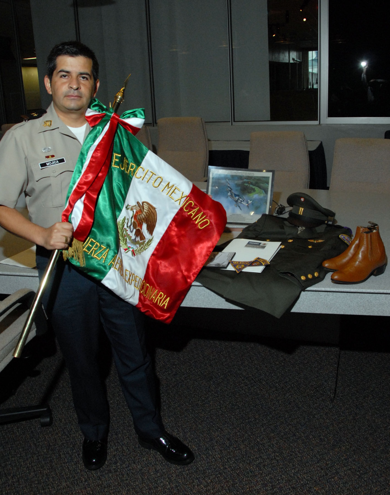 DAYTON, Ohio - Mexican air force Lt. Col. Daniel Mojica stands in front of items while holding the unit colors for the Mexican Expeditionary Air Force (“Fuerza Aérea Expedicionaria Mexicana” or FAEM). These items were donated during a ceremony at the National Museum of the U.S. Air Force. (U.S. Air Force photo)