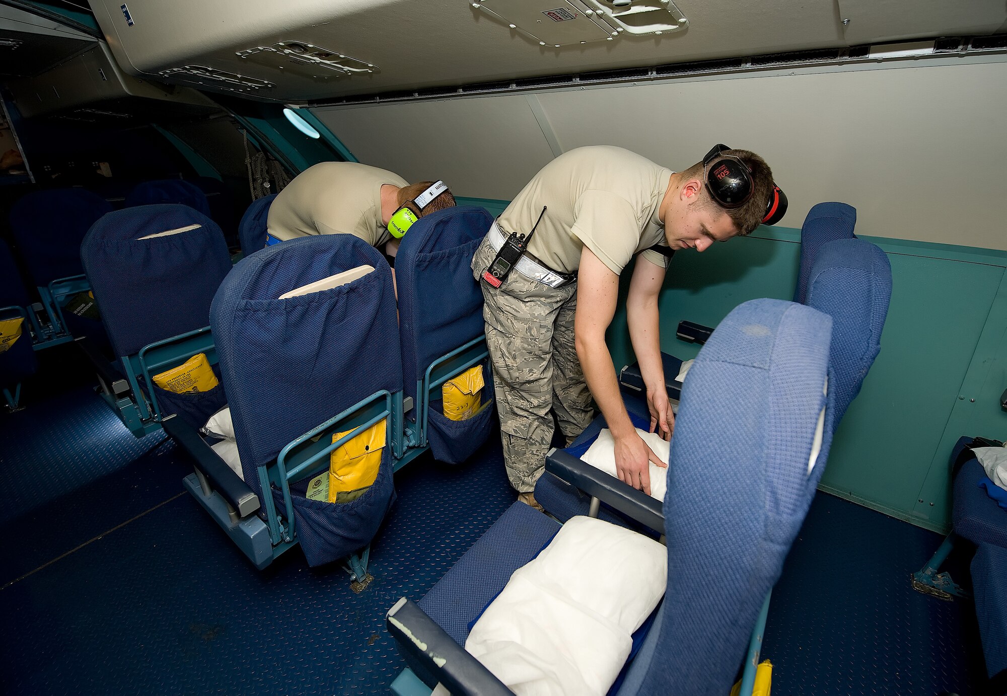 (From left) Airmen 1st Class Alex Osborne and William Dowd, 436th Aerial Port Squadron, straighten pillows and blankets as they prepare a C-5 for departure. Fleet Airmen replenish comfort items such as pillows and blankets and clean the interior of the aircraft. (U.S. Air Force photo/Jason Minto)