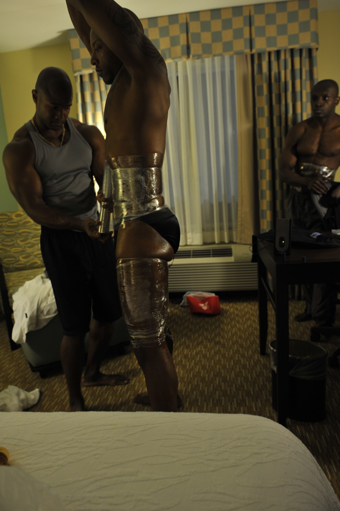 MOODY AIR FORCE BASE, Ga. -- Charles Gloster, Freedom I Fitness Center personal trainer, applies plastic wrap around Senior Airman Rodney Bryant, 824th Security Forces Squadron fire team leader, at their hotel room in Gainesville, Ga., April 10. Applying the wrap helps pull off any excess water, which helps muscles appear tighter and more defined. U.S. Air Force photo by Senior Airman Schelli Jones)
