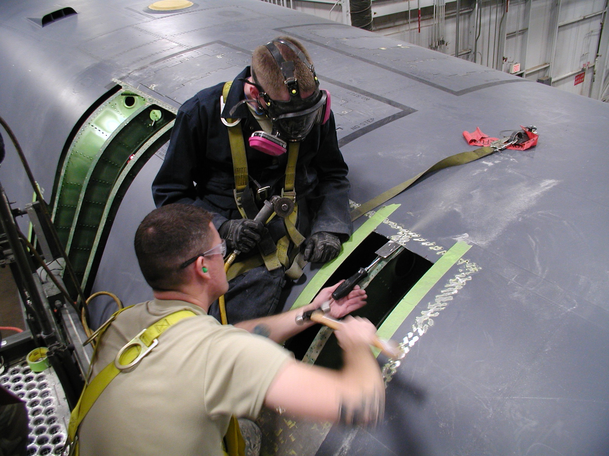 (Front) Staff. Sgt. Cody Danker, 76th Aircraft Maintenance Group, Expeditionary Depot Maintenance Flight crew chief, and Tech. Sgt. Stephen Getten, 76th Aircraft Maintenance Group, Expeditionary Depot Maintenance Flight assistant team chief, remove skin damage from a B-1B Lancer here, April 23. Members of the 76th Aircraft Maintenance Group Expeditionary Depot Maintenance Group worked more than 1,500 man-hours to repair a B-1B Lancer at Ellsworth Air Force Base.(U.S Air Force photo by Tech. Sgt. William Chapin)