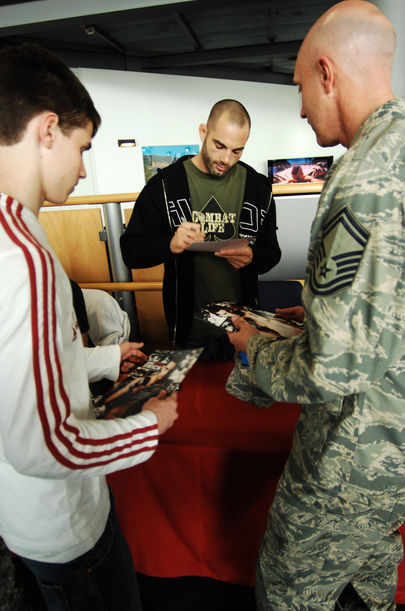 United States Air Force Senior Master Sgt. Jerry Phillips and his son receive an autograph from Michael Swick, Ultimate Fighting Championship fighter, April 28, 2009, Ramstein Air Base, Germany. Three of the UFC fighters visited several United Service Organizations to visit with Airmen and their families. (U.S. Air Force photo by Senior Airman Amber Bressler)