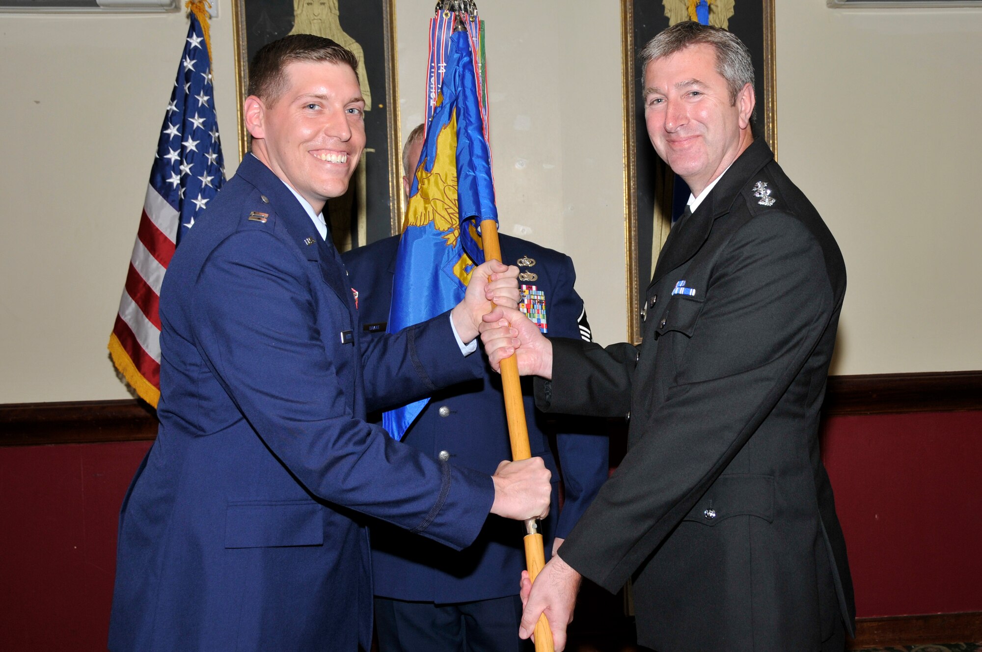 ROYAL AIR FORCE LAKENHEATH, England -- Captain Ian Walker, acting 48th Security Forces commander ,shares the command guidon with Chief Inspector Mike Holdsworth, District Police Commander, Forest Heath Area here April 23, 2009. The newly inducted individuals join 15 others as members of the base’s Honorary Commander Program, which pairs key community leaders with base commanders, to familiarize them with the wing’s mission, operations and Airmen through official and social functions.  (U.S. Air Force photo by Airman 1st Class Perry Aston) 
