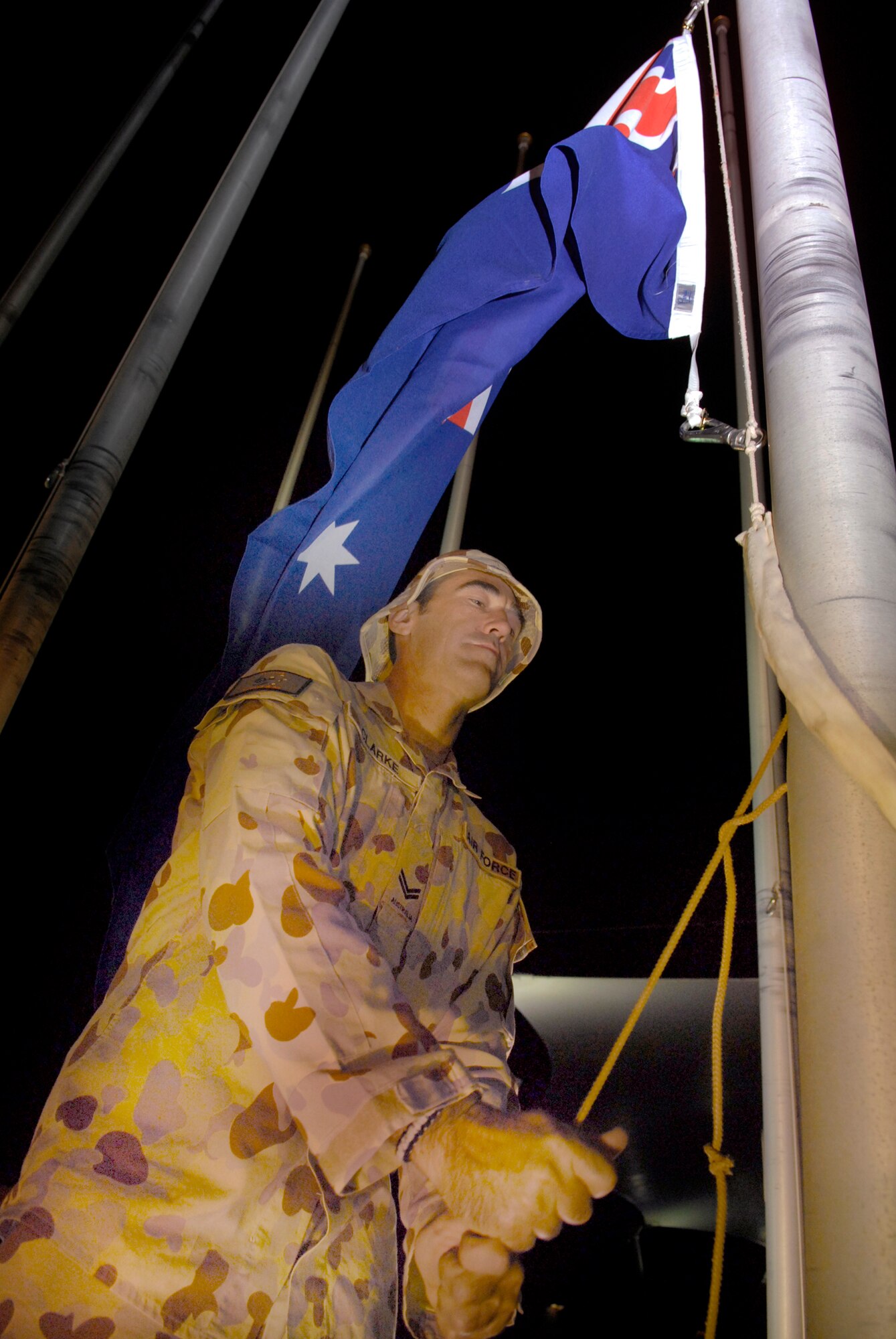 Royal Australian Air Force Corporal Steve Clarke, TE 633.2.2.1, raises the Australian national flag during the Australia and New Zealand Army Corps (ANZAC) Day ceremony, April 25, 2009, at an undisclosed location in Southwest Asia.  ANZAC Day is a national day of remembrance in Australia and New Zealand to honor the members of ANZAC who fought at Gallipoli in World War I and more broadly commemorates all those who have died and served in military operations for the country.  Cpl. Clarke hails from Brisbane, Australia and is deployed from Amberley RAAF Base in support of Operations IRaqi and Enduring Freedom and Combined Joint Task Force - Horn of Africa.  (U.S. Air Force photo/Senior Airman Andrew Satran/released)  