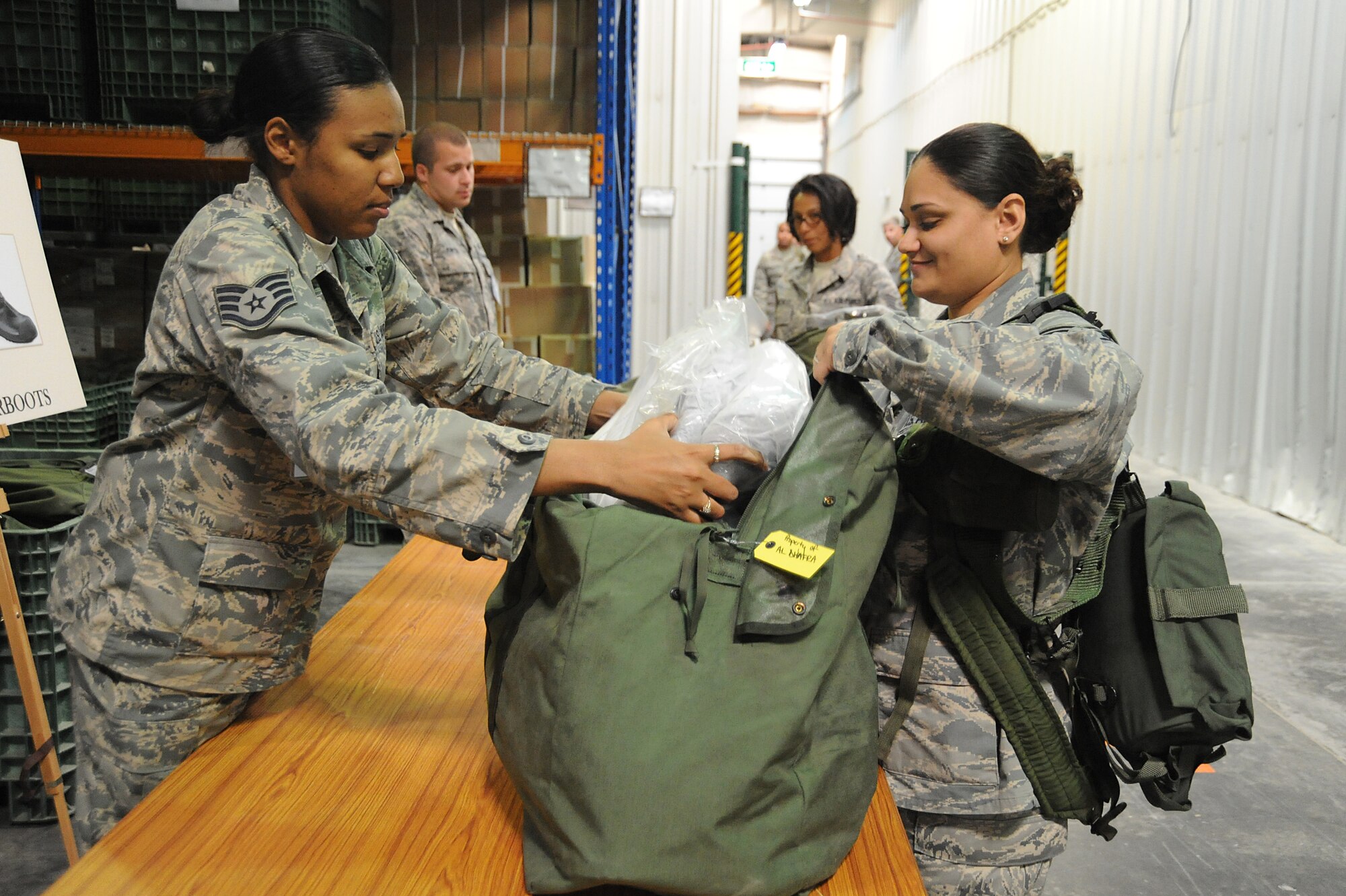 Staff Sgt. Bianca Cox, 380th Expeditionary Logistics Readiness Squadron, packs chemical boots into a C-bag for Staff Sgt. Michelle Gamble, 380th ELRS as she processes through a deployment line during a readiness exercise, April 21 at undisclosed location in Southwest Asia. The 380th ELRS ran the exercise to test the timeliness and capability for redeployment of Airmen. Sergeant Cox is deployed from Eglin AFB, Fla. and hails from Hampton, Va. Sergeant Gamble is deployed from Holloman AFB, N.M. and hails from Spring Hill, Fla. (U.S. Air Force photo by Senior Airman Brian J. Ellis) (Released)
