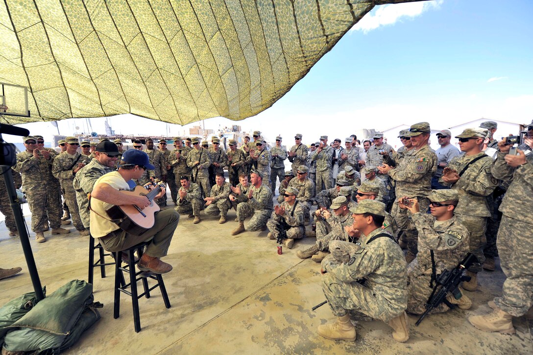 Even without electricity, the show must go on. Toby Keith and his crew performed acoustic concert at the remotest of small bases such as this at the Boris COP, held under the temporary shade of a giant, tented camouflaged tarp. This allowed the troops a very close and intimate distance from the two performers, Toby Keith, left, and Scotty Emerick. USO Courtesy photo by Dave Gatley