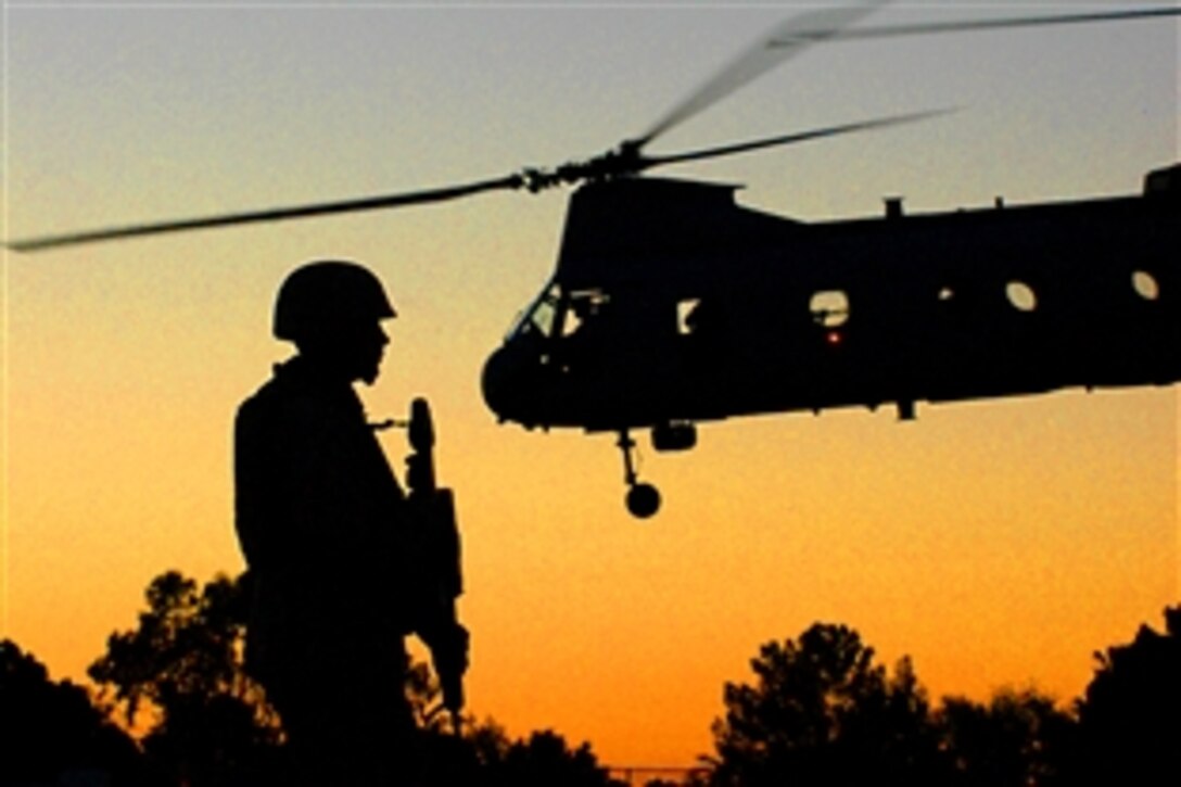 As a CH-46 Sea Knight lifts off behind him, U.S. Marine Lance Cpl. Charles E. Weber guards the perimeter of a makeshift landing zone at Centennial Middle School in Yuma, Ariz., during a simulated evacuation exercise of U.S. citizens from a foreign country in the event of a crisis, April 17, 2009. The city of Yuma allows the Marine Corps to use local parks and school sports fields as training areas.