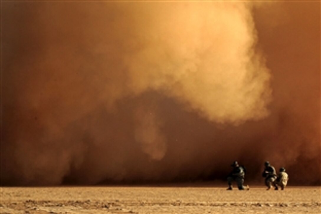 Service members assigned to the Combined Joint Task Force-Horn brace for a wall of dirt and rocks created by the prop wash from a Marine Corps CH-53E helicopter as it takes off from a dry lake bed during a search and rescue exercise, Grand Bara, Djibouti, April 23, 2009.