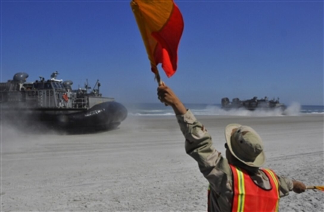 A U.S. Navy landing signal officer with Beachmaster Unit 2 directs two 87-foot landing craft, air cushioned from Assault Craft Unit 4 to their landing zones to unload soldiers and Marines from Canada, Chile, Brazil, Peru and Uruguay onto a Mayport, Fla., beach during an amphibious training exercise on April 4, 2009.  Assault Craft Unit 4 is underway with the amphibious transport dock ship USS Mesa Verde (LPD 19) as part of UNITAS Gold, a multinational exercise that aims to increase interoperability among participating nations.  