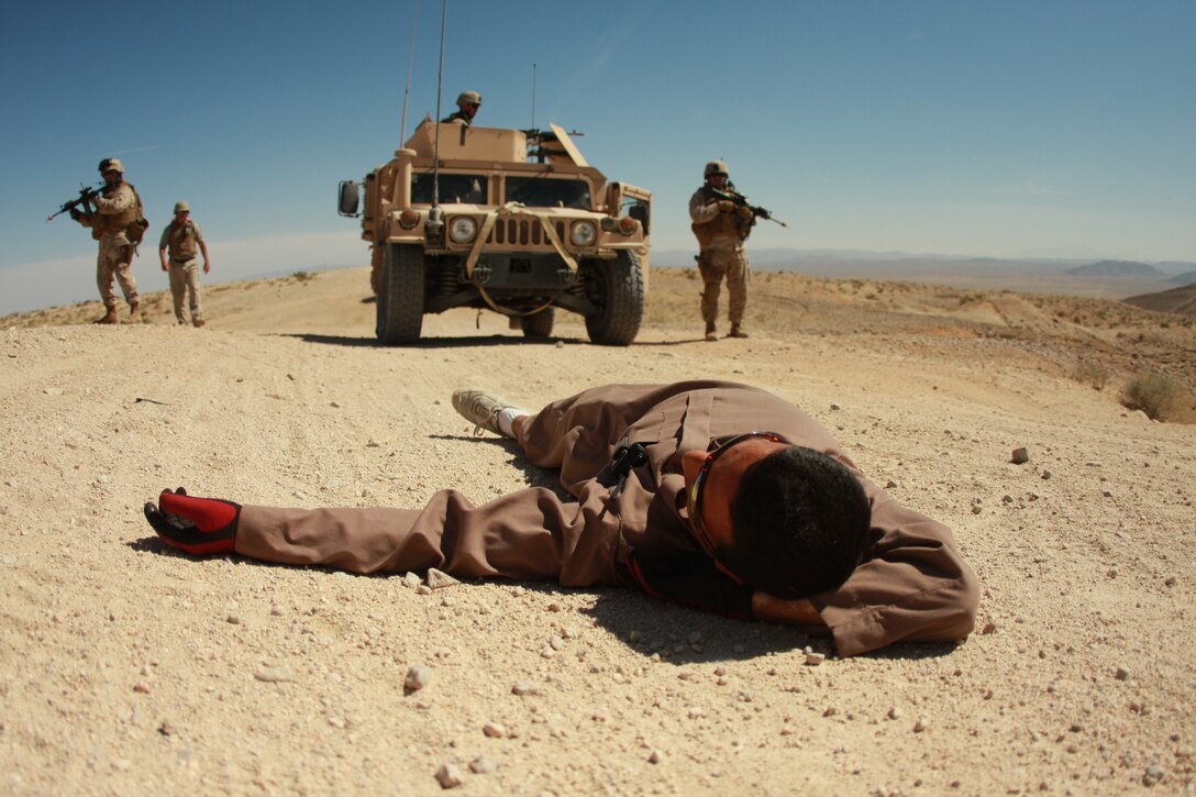 An Iraqi role player with the Advisor Training Group lies still as Marines and sailors training at ATG dismount their vehicle. Transition teams met with a small arms assault May 1 during their training at the Combat Center’s Gypsum Ridge training area.