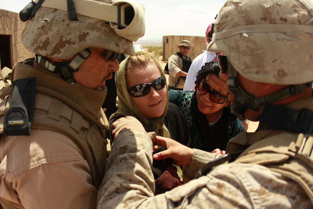 2nd Lt. Joshua Murray and an Iraqi role player, tend to Krista Galyean, a role player with the Advisor Training Group, during a mass casualty exercise at the Combat Center May 1 during the transition team’s training.