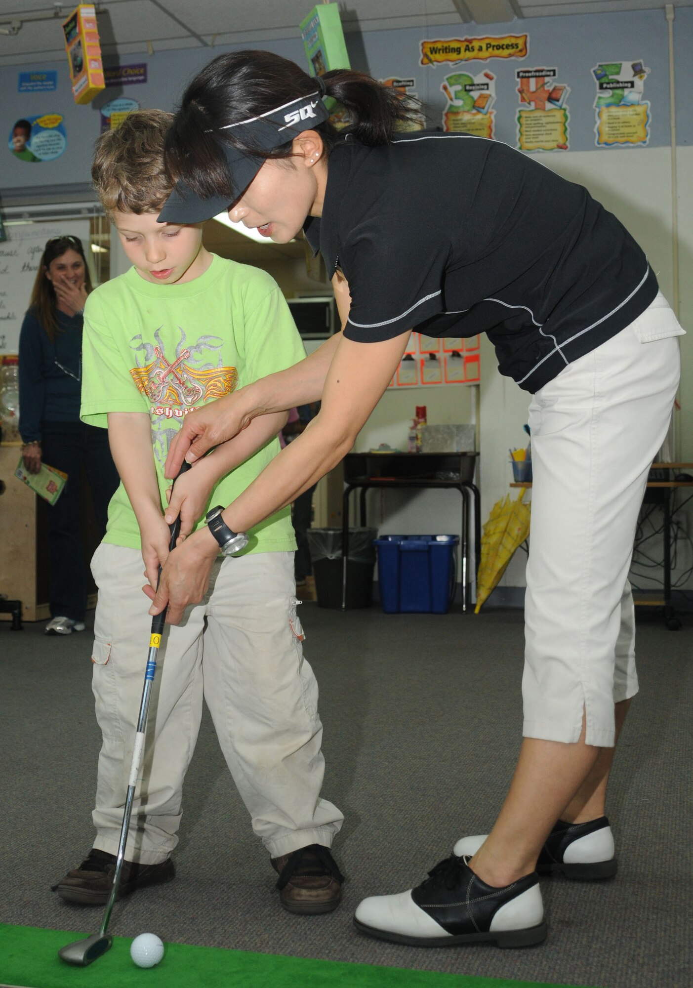 YOKOTA AIR BASE, Japan-- Kyoko Romano, Tama Hills Golf Course instructor, shows Declan Denny how to putt April 30 during the Family Fit Picnic at Yokota West Elementary School. The picnic, which included fit activities such as Zumba, yoga, aerobics and other games, was the final event to celebrate April as the Month of the Military Child. (U.S. Air Force photo/Airman Sean Martin)
