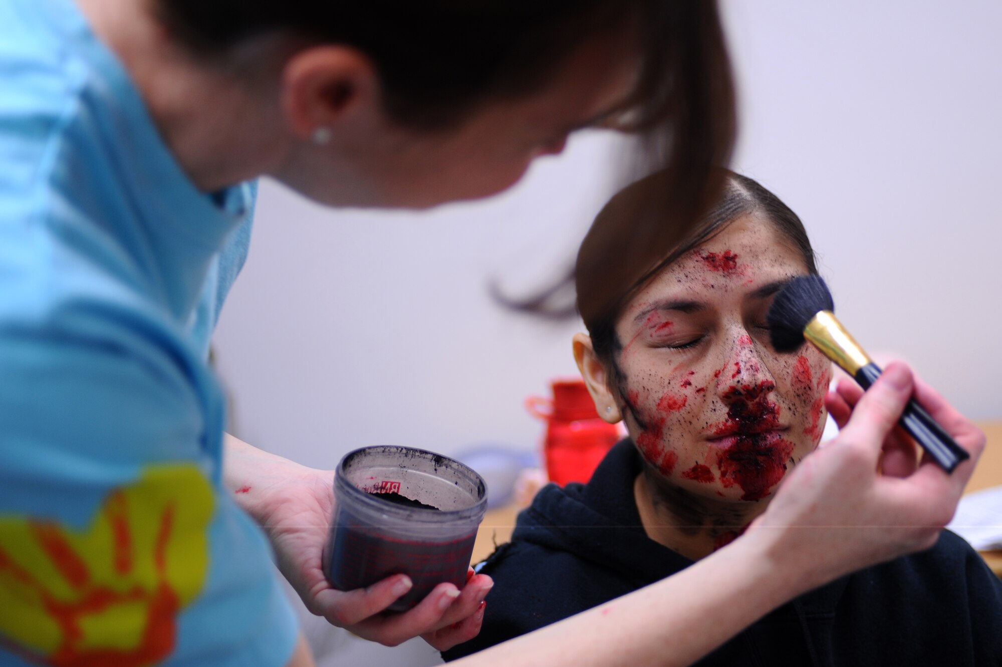 Senior Airman Ashley Barlow (left), 28th Medical Support Squadron patient administrator, applies moulage make-up to Staff Sgt. Carmen Matta’s face, 28th Medical Support Squadron NCO in-charge of patient administrators, before a major accident response exercise here, April 30. The exercise was tailored specifically to prepare for the Dakota Thunder air show. (U.S. Air Force photo/Senior Airman Kasey Zickmund)
