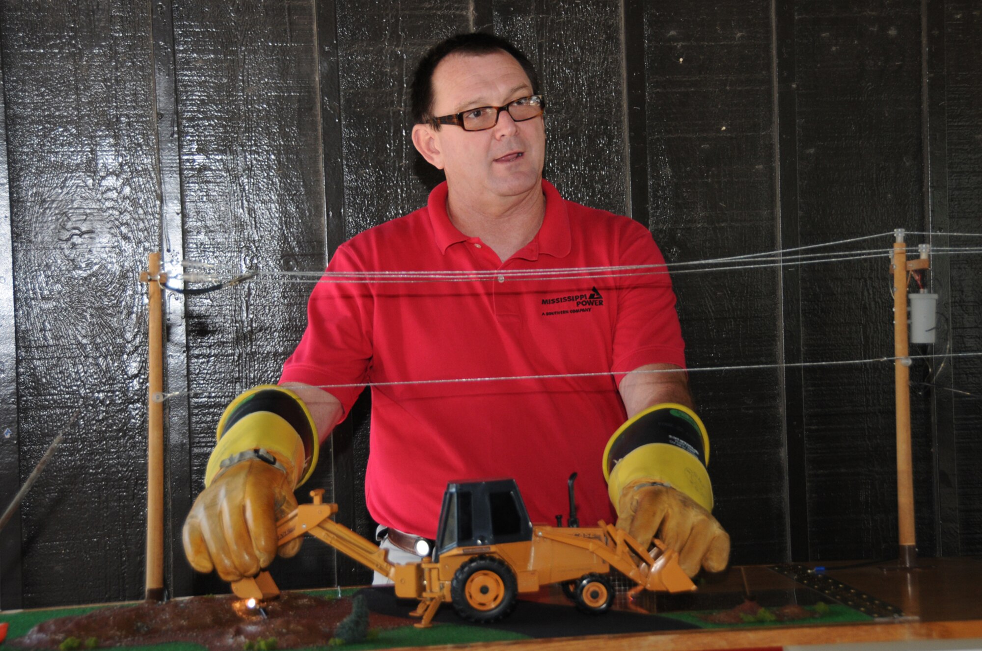 Archie Reeves, Mississippi Power Co., demonstrates the importance of safety when dealing with power lines and underground utility lines.  The company gave away energy-saving light bulbs at the expo.  (U.S. Air Force photo by Kemberly Groue)