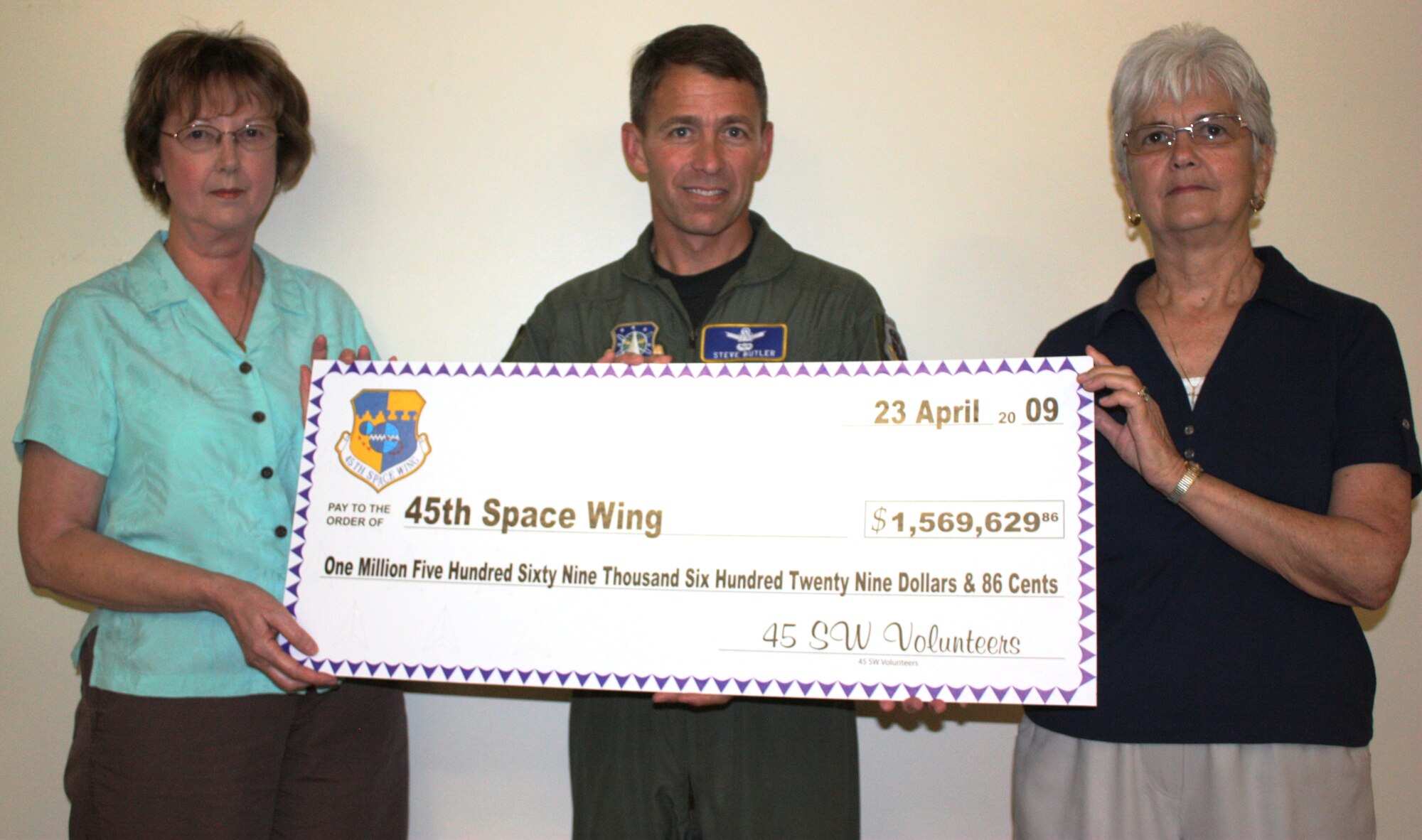 Marlene Haffield (left) and Shirley Osborne (right) of Family Services present a check representing the total dollar amount of wages and revenue saved by the time invested from local volunteers to 45th Space Wing Vice Commander Col. Stephen Butler April 23. (U.S. Air Force photo/Tech. Sgt. Lisa Luse)