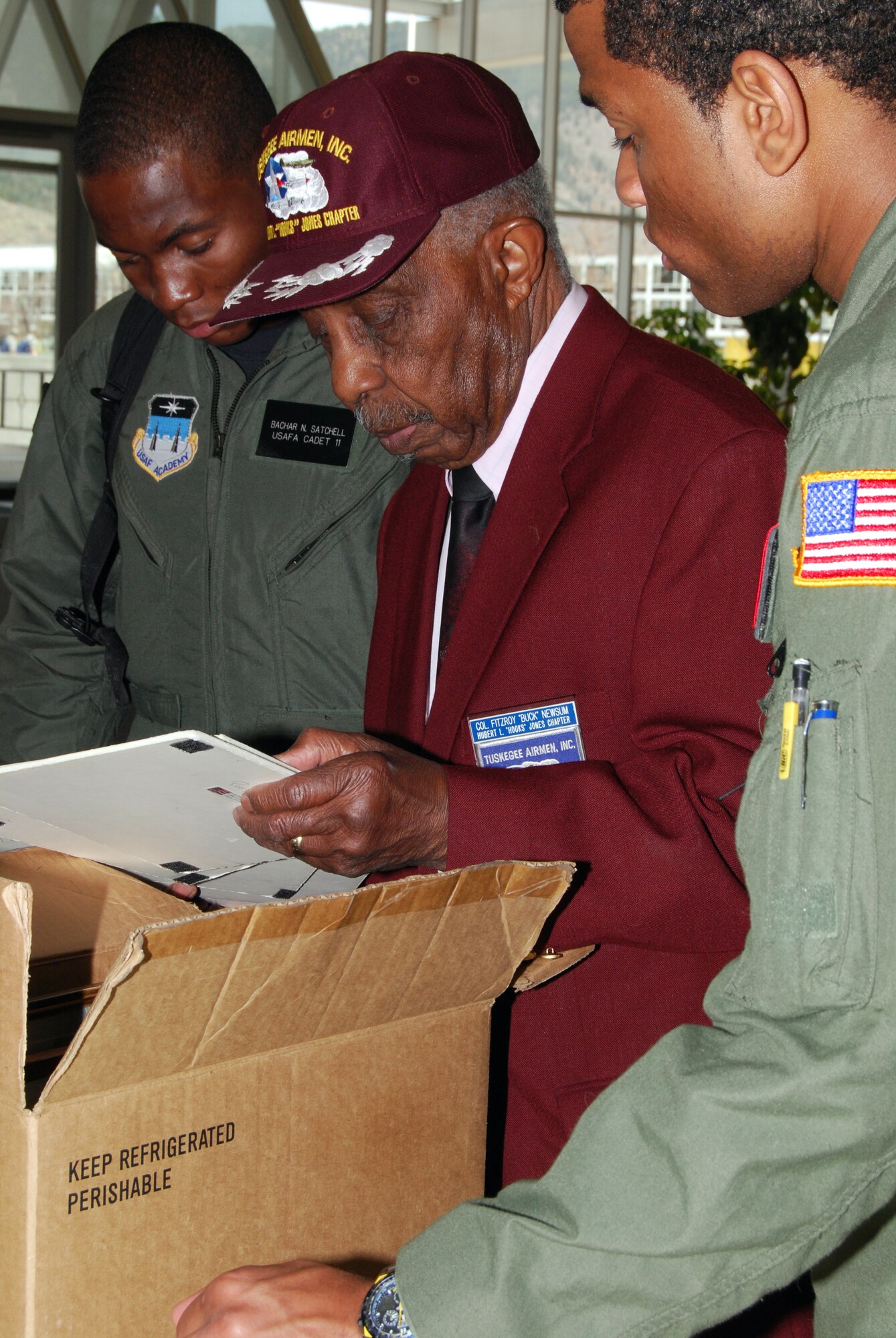 Retired Col. Fitzroy "Buck" Newsum shows Tuskegee Airmen memorabilia to Cadets 3rd Class Bachar Satchell and Kyle Foley during a visit to the U.S. Air Force Academy, Colo., April 24. Mr. Newsum, one of the original Tuskegee Airmen, served under Brig. Gen. Benjamin O. Davis Sr. and then-Col. Benjamin O. Davis Jr. He was assigned to the 617th Bombardment Group during World War II. (U.S. Air Force photo/Staff Sgt. Don Branum)