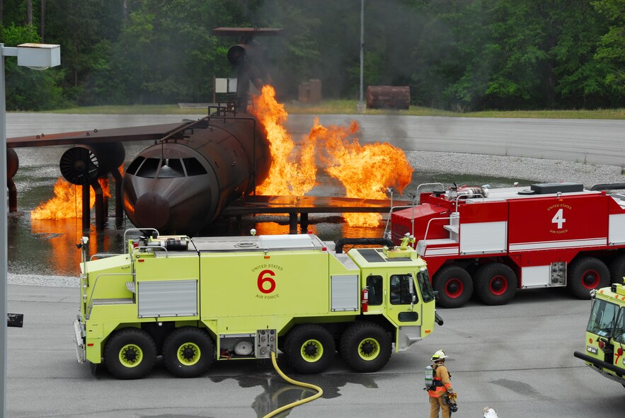 Robins fire trucks surround the burn simulator after extinguishing the first round of training.  U. S. Air Force photo by Ed Aspera