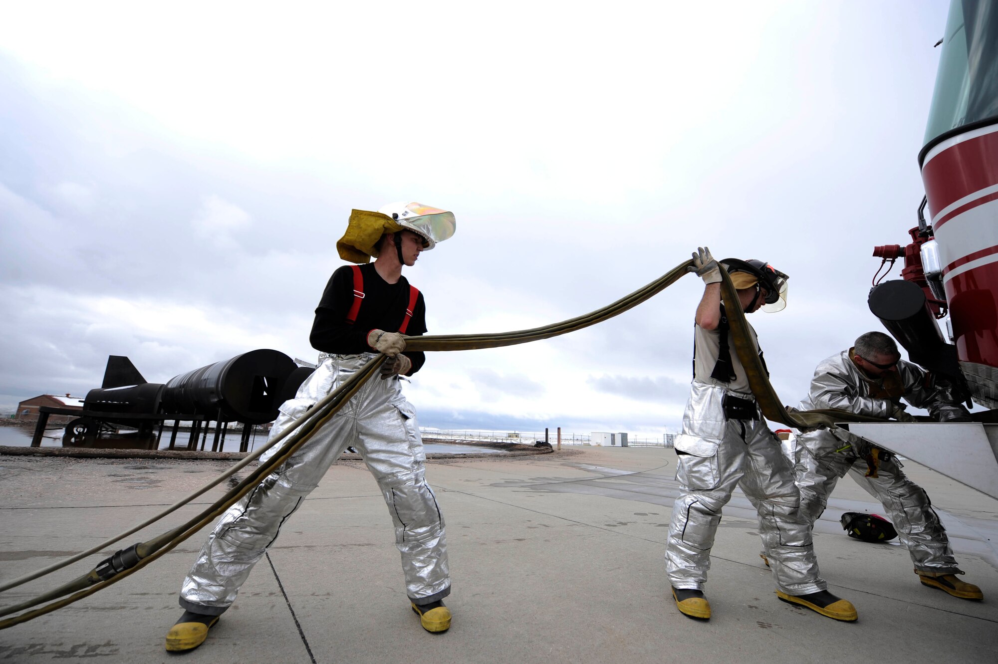 (Left to Right) Airmen First Class Dale Petersdorf and Jason Moore, 28th Civil Engineer Squadron firefighters, and William Cina, 28th Civil Engineer Squadron operator, load a triple layer hose into a fire truck here, April 27. Ellsworth's fire department trains every day to respond to emergencies. (U.S. Air Force photo by Airman First Class Corey Hook)
