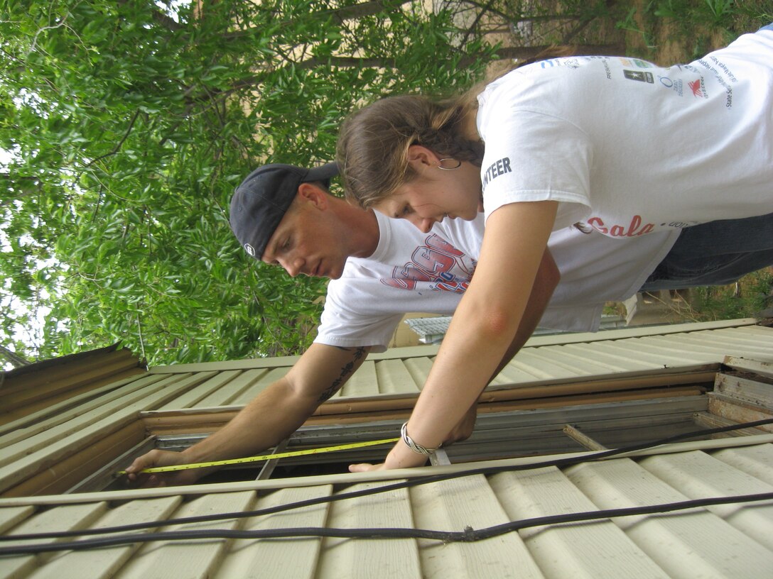 Tech. Sgt. Terry Doll, 360th TRS, and Senior Airman Lindsay Dereadt, Health and Wellness Center, measure for a replacement window during Christmas in Action 2009. The Burkburnett house team replaced a roof, windows and bathroom for needy residents. (U.S. Air Force photo/Debi Smith)