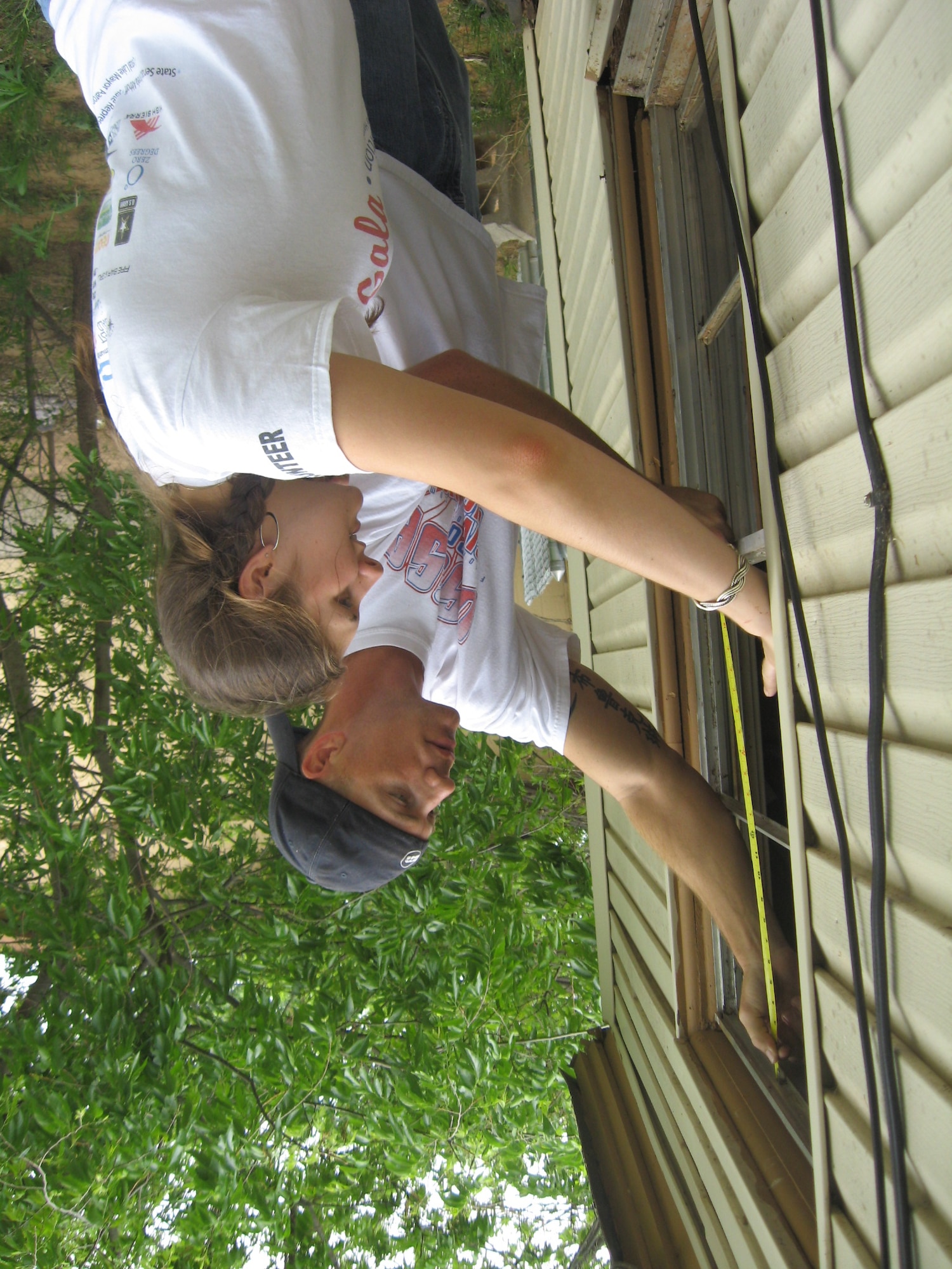 Tech. Sgt. Terry Doll, 360th TRS, and Senior Airman Lindsay Dereadt, Health and Wellness Center, measure for a replacement window during Christmas in Action 2009. The Burkburnett house team replaced a roof, windows and bathroom for needy residents. (U.S. Air Force photo/Debi Smith)