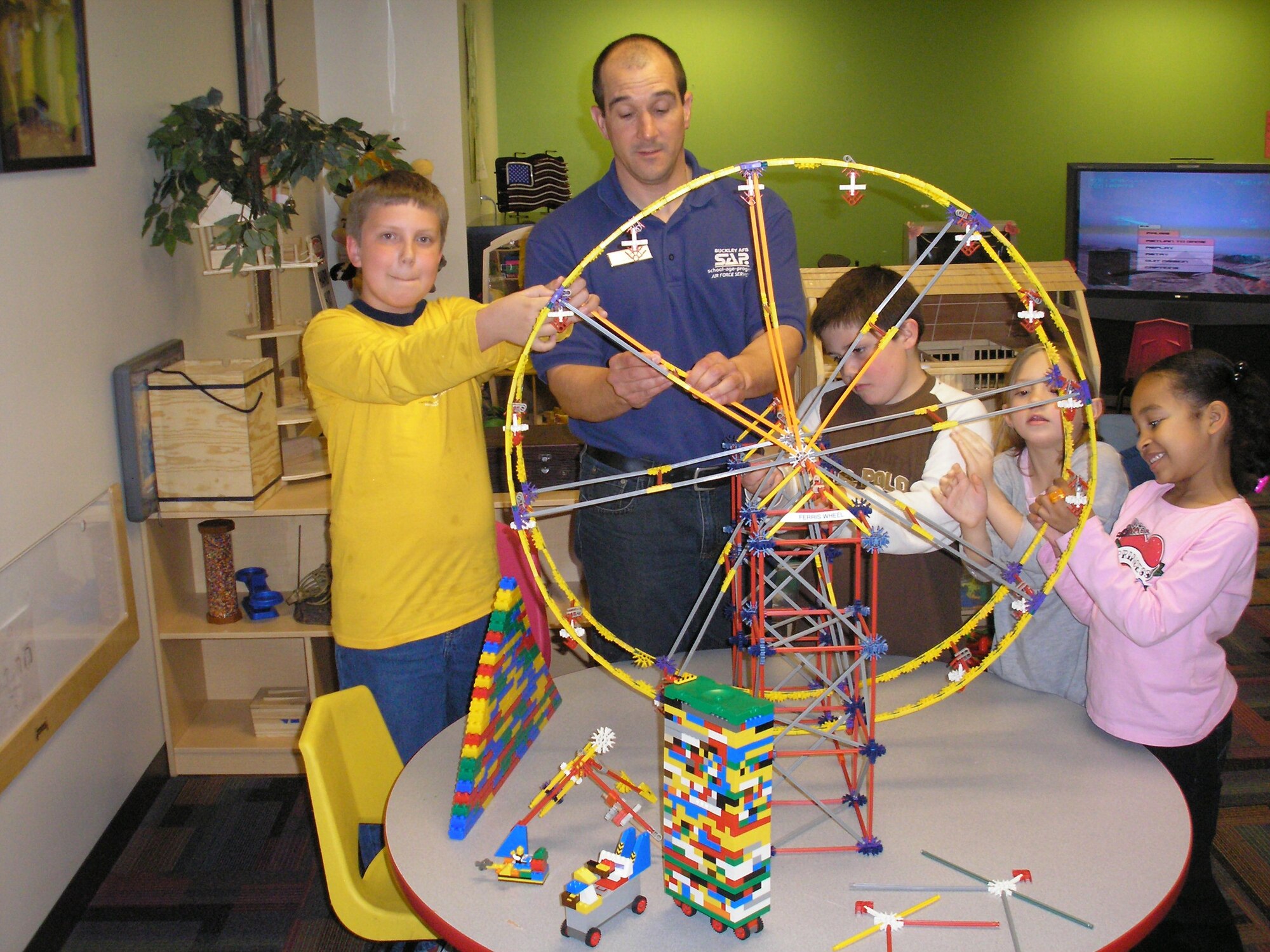 BUCKLEY AIR FORCE BASE, Colo. -- Tom Cox assists children in the Youth Program in building a ferris wheel.  Mr. Cox, 460th Force Support Squadron Youth Program Director, is Team Buckley's Warrior of the Week for May 8-14.  He hails from Menominee, Mich. (Courtesy photo)   