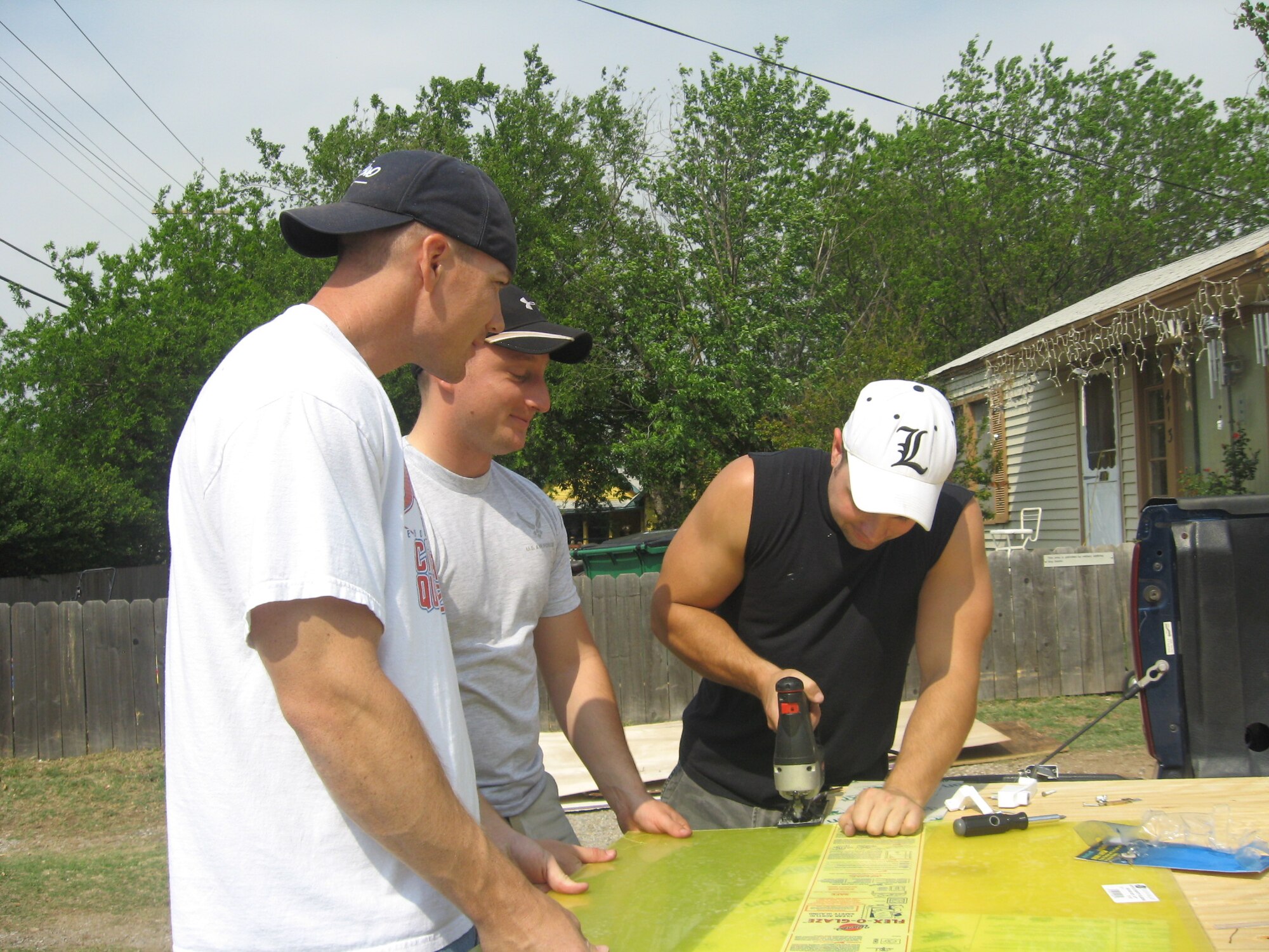 Staff Sgt. Justin Clark, Staff Sgt. Jason Bales and Tech. Sgt. Terry Doll are Team Sheppard members from the 360th TRS, are cutting plexi-glass as safety window replacements for a Burkburnett house renovation April 25 as part of Christmas in Action 2009.(U.S. Air Force photo/Debi Smith)