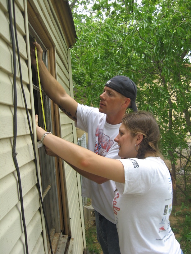 Tech. Sgt. Terry Doll, 360th TRS, and Senior Airman Lindsay Dereadt, Health and Wellness Center, measure for a replacement window during Christmas in Action 2009.  The Burkburnett house team replaced a roof, windows and bathroom for needy residents. (U.S. Air Force photo/Debi Smith)