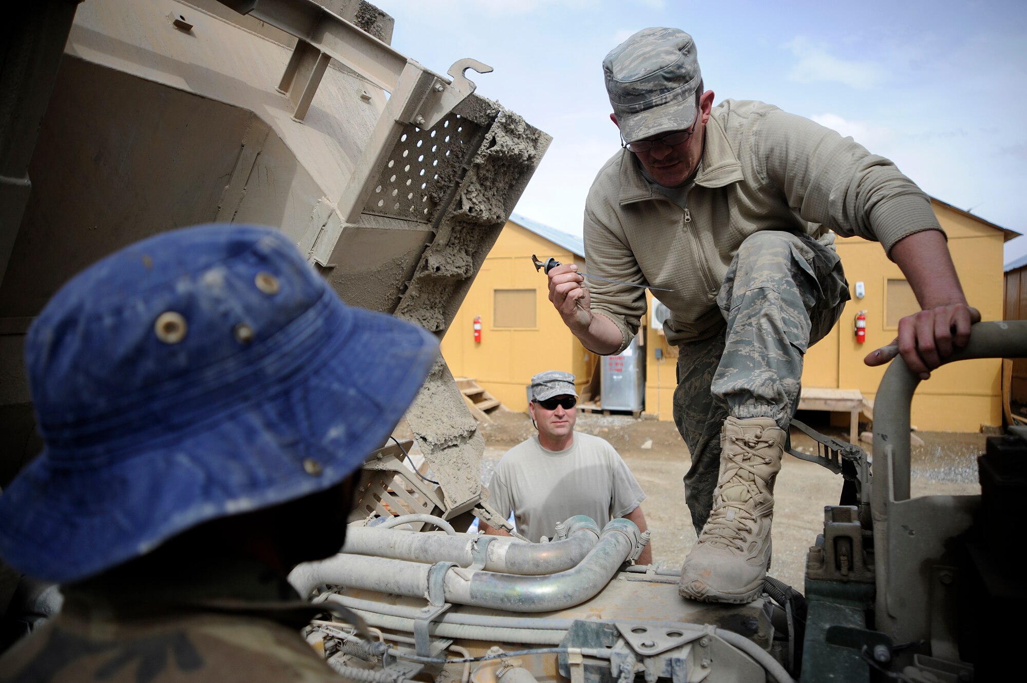 U.S. Air Force Master Sgt. Alexander Bryant (left), Non-Commissioned Officer in Charge of the vehicle maintenance unit assigned to the Provincial Reconstruction Team, Forward Operating Base, Gardez, Afghanistan and Staff Sgt. Robert Reich a vehicle maintainer,  help a local national check the oil level of a Medium Tactical Vehicle before they release it for combat operations, April 20, 2009. Master Sgt. Bryant is deployed from the 30th Logistics Readiness Squadron, Vandenburg Air Force Base, CA and Staff Sgt. Reich is deployed from the 35th LRS, Misawa Air Base, Japan. (U.S. Air Force photo by Staff Sgt. Shawn Weismiller)