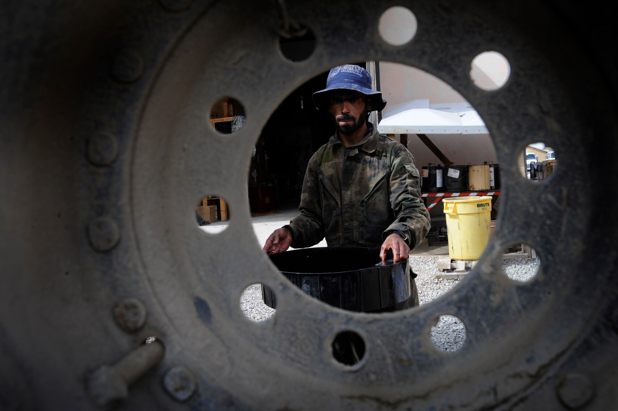 A local national working for the Provincial Reconstruction Team's vehicle maintenance unit carries a vat of oil he drained out of a Medium Tactical Vehicle, April 20, 2009. Forward Operating Base Gardez, Afghanistan.  (U.S. Air Force photo by Staff Sgt. Shawn Weismiller)