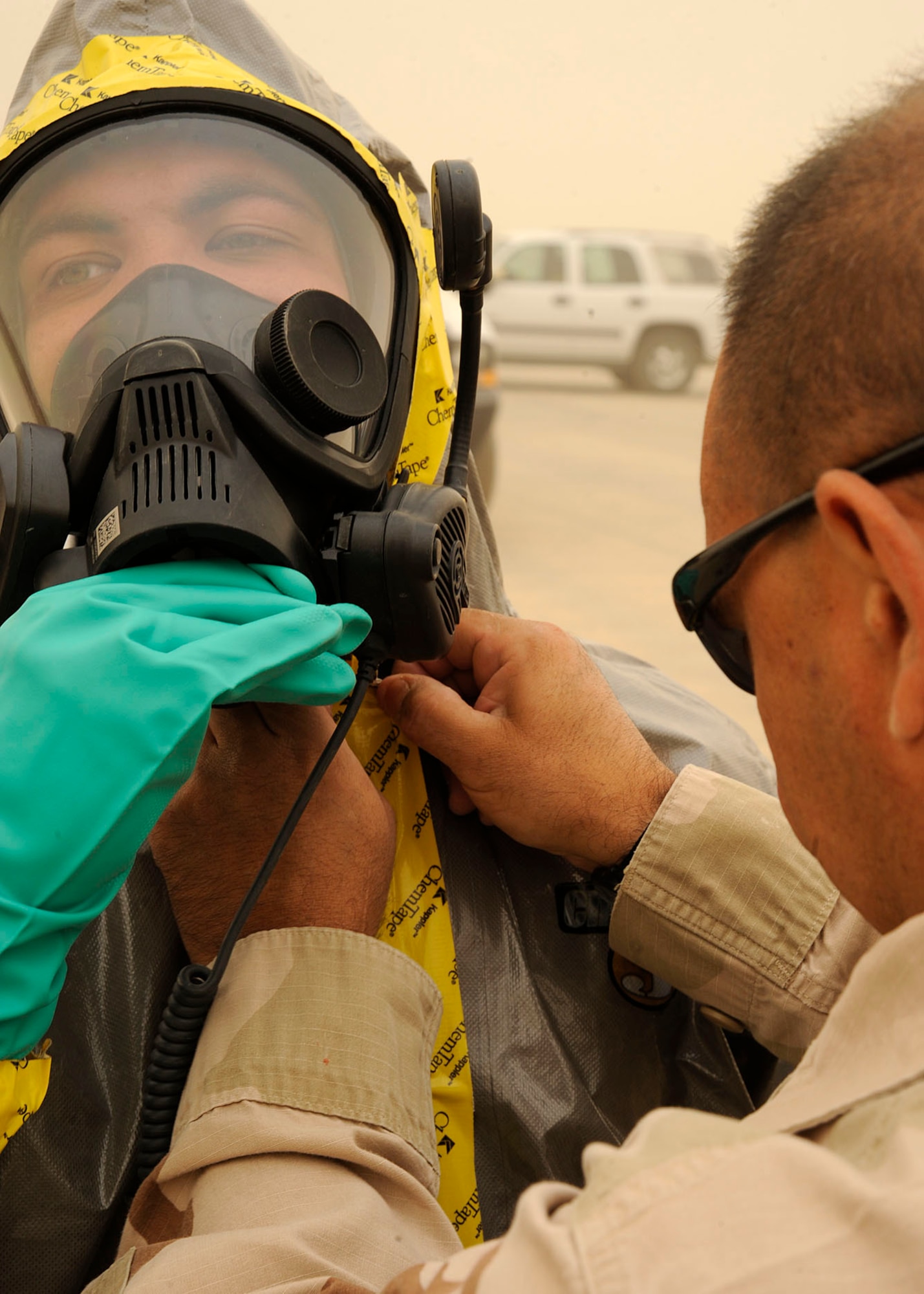 Tech. Sgt. Peter Mickiewicz, 447th Expeditionary Civil Engineer Squadron, secures a piece of chemical tape around the mask of Senior Airman Tyrone Fisher, 447th ECES, Camp Stryker, Iraq April 24, 2009. All mail that comes into Baghdad that is improperly labeled, doesn’t have a return address or gets lost in the system has to be inspected before they can be processed and get it to the intended destination. The Iraqi government returns the mail to the Joint Military Mail Terminal on good faith but the military here has to take necessary precautions because the mail left the military postal system. When the JMMT gets the mail back from the Iraqi government it is ran through x-ray, inspected by military working dogs and then inspected by the 447th ECES emergency management flight for suspicious and/or hazardous materials which might have inadvertently come in contact with or intentionally added to the mail.  The Airmen, armed with chemical suits and hazardous material sensors make their way downrange in teams of three, where the mail is stored and run test on the packages for radiological, chemical and biological material. The inspection process is a joint effort between emergency management team, readiness, the fire department, and biological engineers. Sergeant Mickiewicz is deployed from the 157th Air Refueling Wing, New Hampshire Air National Guard, is a native of Cambridge, Massachusetts.  Airman Fisher is deployed from the 181st Intelligence Wing, Indiana Air National Guard and is a native of Indianapolis. (U.S. Air Force photo by: Senior Airman Jacqueline Romero)
