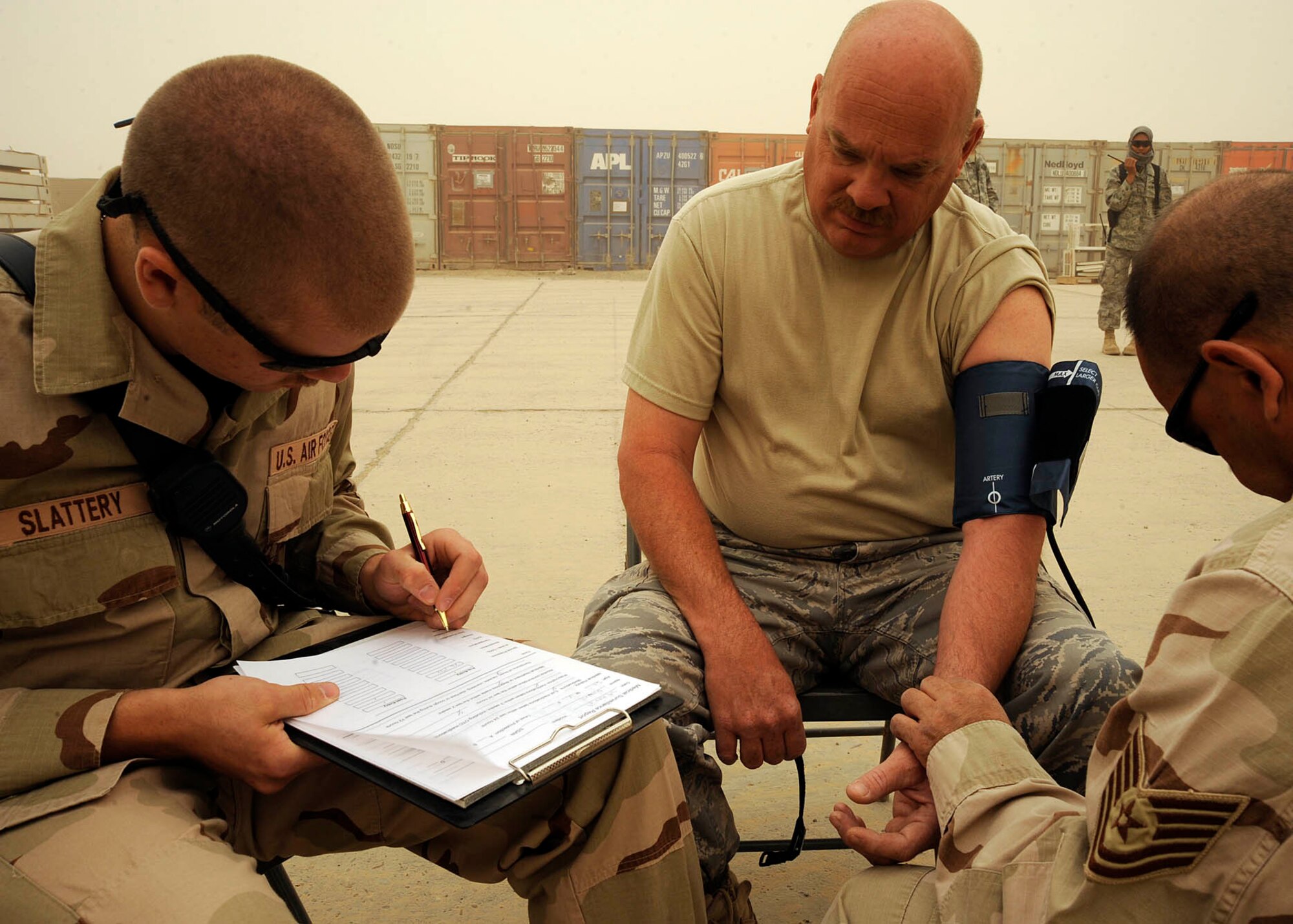Senior Airman Matthew Slattery (left) and Tech. Sgt. Peter Mickiewicz (right), take Tech. Sgt. Steve Gaunt’s, 447th Expeditionary Civil Engineer Squadron emergency management flight, blood pressure and vitals making sure he is healthy enough to perform the duties involved in his chemical gear, Camp Stryker, Iraq April 24, 2009. All mail that comes into Baghdad that is improperly labeled, doesn’t have a return address or gets lost in the system has to be inspected before they can be processed and get it to the intended destination. The Iraqi government returns the mail to the Joint Military Mail Terminal on good faith but the military here has to take necessary precautions because the mail left the military postal system. When the JMMT gets the mail back from the Iraqi government it is ran through x-ray, inspected by military working dogs and then inspected by the 447th ECES emergency management flight for suspicious and/or hazardous materials which might have inadvertently come in contact with or intentionally added to the mail.  The Airmen, armed with chemical suits and hazardous material sensors make their way downrange in teams of three, where the mail is stored and run test on the packages for radiological, chemical and biological material. The inspection process is a joint effort between emergency management team, readiness, the fire department, and biological engineers.  Airman Slattery and Sergeant Mickiewicz are deployed from the 157th Air Refueling Wing, New Hampshire Air National Guard. Airman Slattery is a native of Exeter, N.H. Sergeant Mickiewicz is a native of Cambridge, Mass. Sergeant Gaunt is deployed from the 117th Air Refueling Wing Alabama Air National Guard, is a native of Marietta, Ga. (U.S. Air Force photo by Senior Airman Jacqueline Romero)