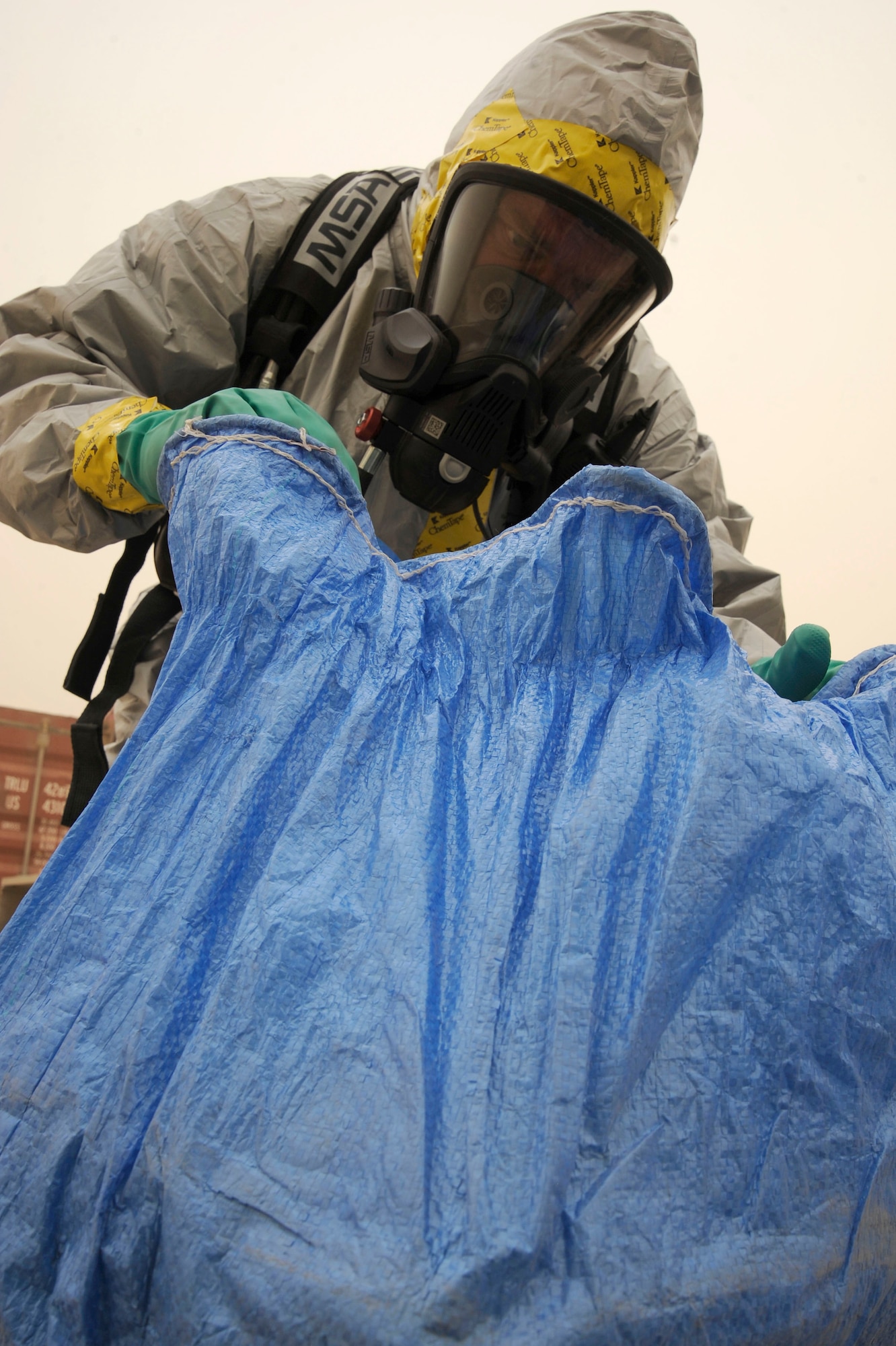 Tech. Sgt. Steve Gaunt, 447th Expeditionary Civil Engineer Squadron emergency management flight, looks through a bag of mail to see if there are any suspicious packages, Camp Stryker, Iraq April 24, 2009. All mail that comes into Baghdad that is improperly labeled, doesn’t have a return address or gets lost in the system has to be inspected before they can be processed and get it to the intended destination. The Iraqi government returns the mail to the Joint Military Mail Terminal on good faith but the military here has to take necessary precautions because the mail left the military postal system. When the JMMT gets the mail back from the Iraqi government it is ran through x-ray, inspected by military working dogs and then inspected by the 447th ECES emergency management flight for suspicious and/or hazardous materials which might have inadvertently come in contact with or intentionally added to the mail.  The Airmen, armed with chemical suits and hazardous material sensors make their way downrange in teams of three, where the mail is stored and run test on the packages for radiological, chemical and biological material.  The inspection process is a joint effort between emergency management team, readiness, the fire department, and biological engineers. Sergeant Gaunt is deployed from 117th Air Refueling Wing Alabama Air National Guard, is a native of Marietta, Ga.  (U.S. Air Force photo by Staff Sgt. Tim Beckham)