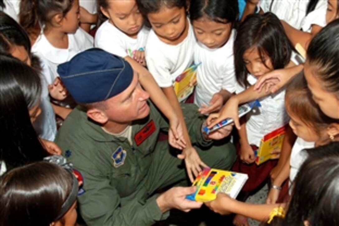U.S. Air Force Lt. Col. Jack Maxiner hands out school supplies to Filipino children at the Sapangbato village community center as part of a community relations event in Angeles City, Philippines, April 25, 2009. Maxiner is the 63rd Fighter Squadron commander on Luke Air Force Base, Ariz.
