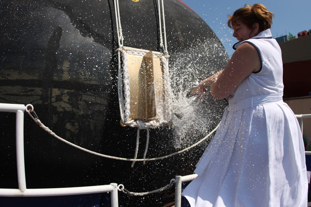 Deb Dunham, the mother of Medal of Honor recipient Cpl. Jason Dunham and sponsor of the ship bearing her son's name, smashes the ceremonial bottle of champagne against the bow of the Navy's newest AEGIS-class destroyer, the USS Jason Dunham, after officially christening her during the Aug. 1 ceremony at Bath Iron Works in Bath, Maine.