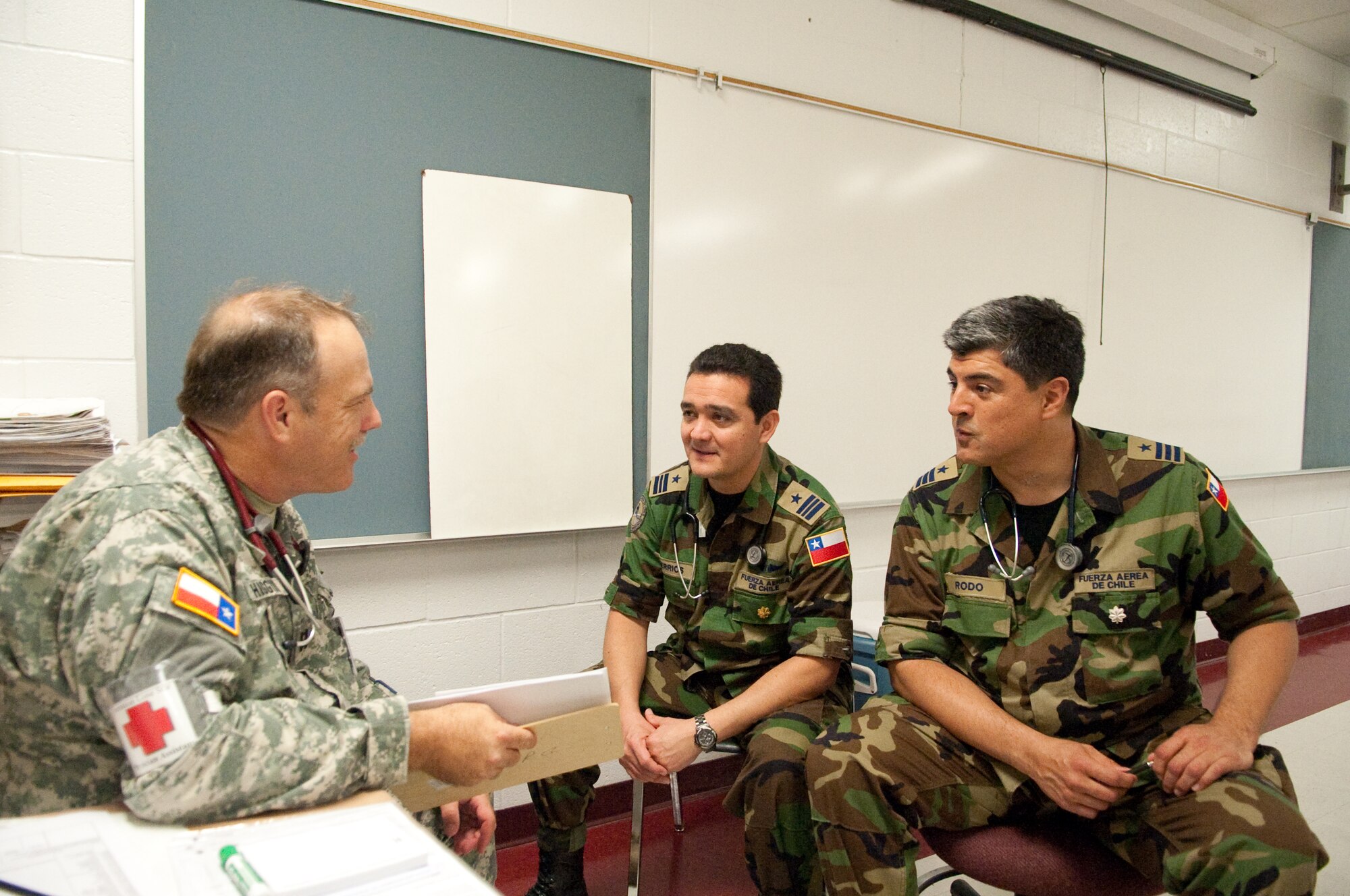 Chilean Military Air Force Lt. Col. Alger Rodo, a specialist in colorectal surgery, and Maj. Raul Berrios, a thoracic surgeon discuss with State Guard Capt. Wood, medical brigade, triage procedures at Pharr-San Juan-Alamo High School. The surgeons participate in an international exchange program between the State of Texas and the Republic of Chile during Operation Lone Star held at Pharr, Texas, July 29, 2009. (U.S. Air Force photo by Senior Master Sgt. Elizabeth Gilbert)